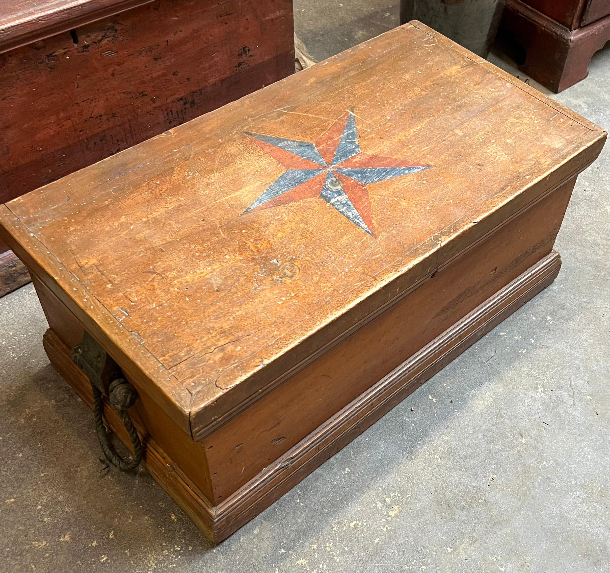 Coffre de mer en pin du 19e siècle dans sa finition d'origine.  L'extérieur du couvercle est décoré d'une rose des vents/étoile incisée et peinte en bleu et rouge.  Intérieur équipé de deux caisses et d'un tiroir inférieur.  Seaux latéraux peints