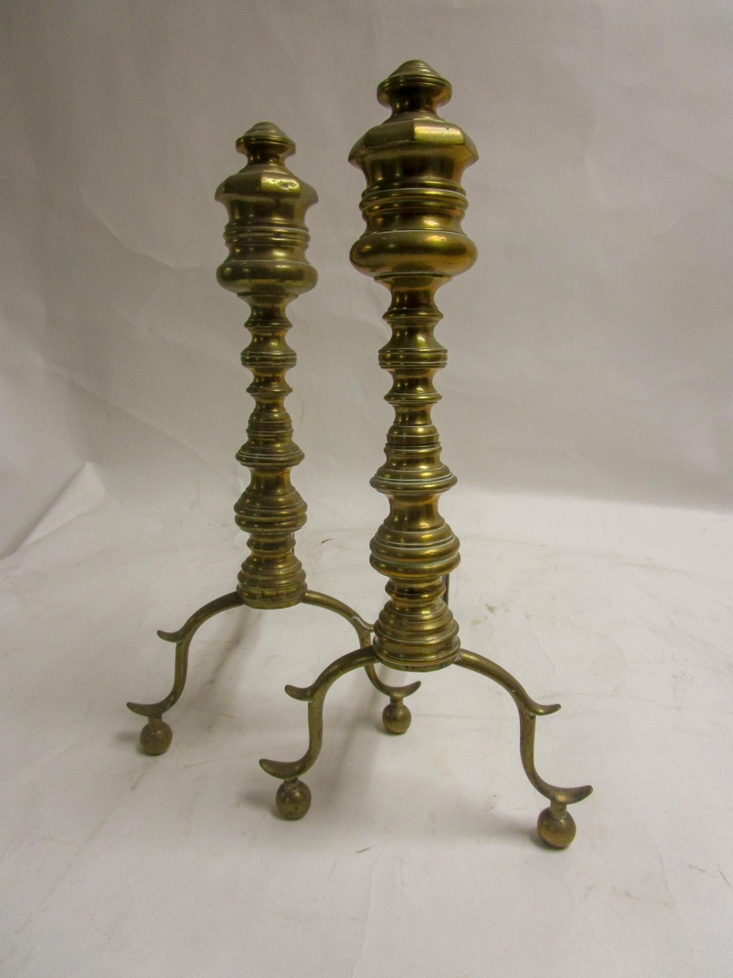 This classical pair of early 19th century English Regency andiron firedogs feature multiple turnings and perch delicately on ball feet. Very sturdy construction.