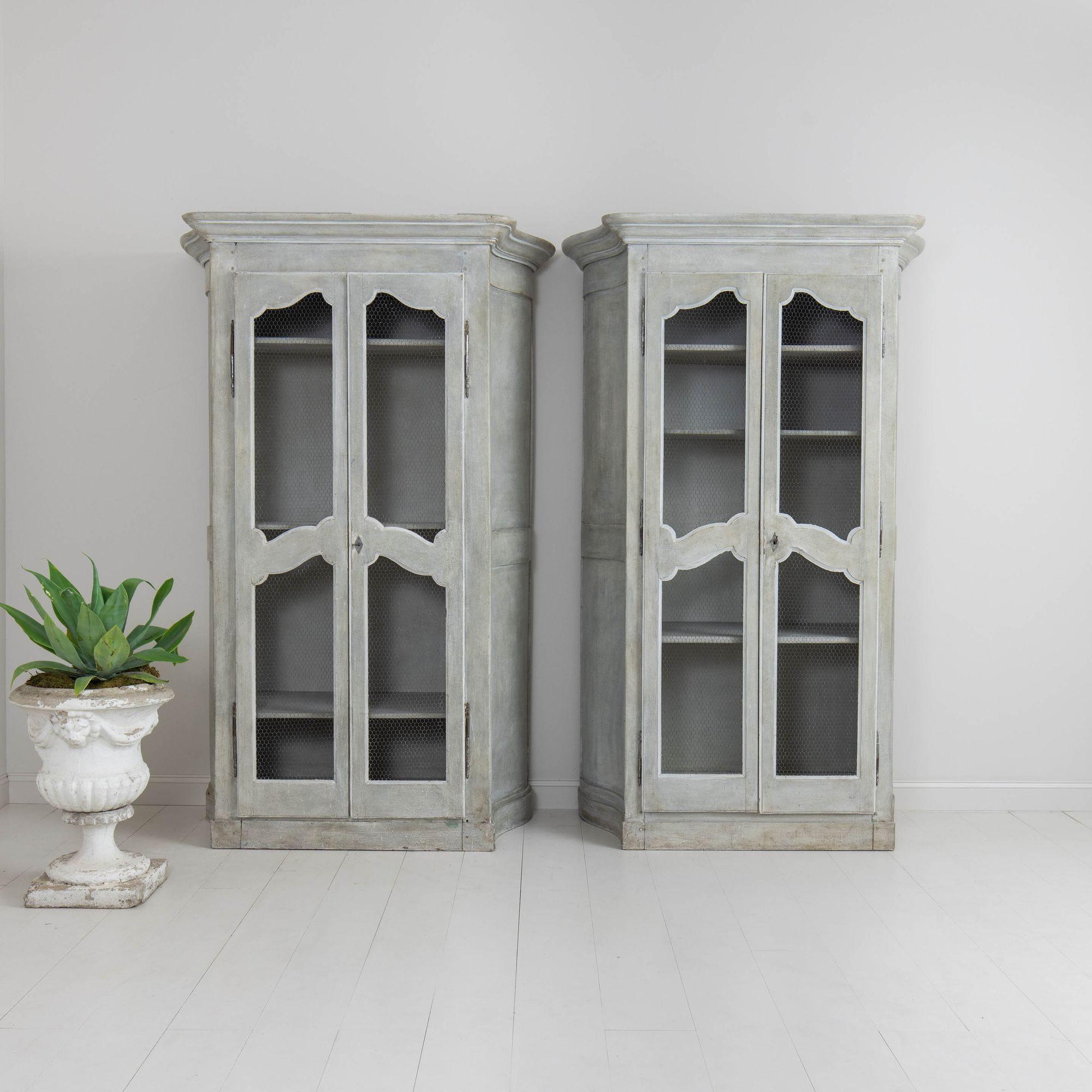 A matched pair of grand, French two-door cabinets from the 19th century with wire mesh door fronts and canted serpentine sides, supported by shaped box plinths. Circa 1840. There are three adjustable shelves in each cabinet. The cabinets disassemble