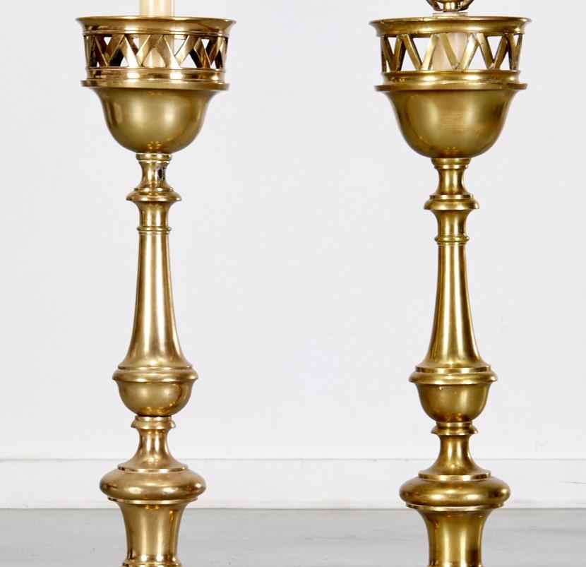 19th c. Dutch large ecclesiastical brass candlesticks converted to table lamps. They are heavy and substantial, each with a single sconce on a turned column culminating on a triform base. The drip pans have an unusual basket form. These lamps could