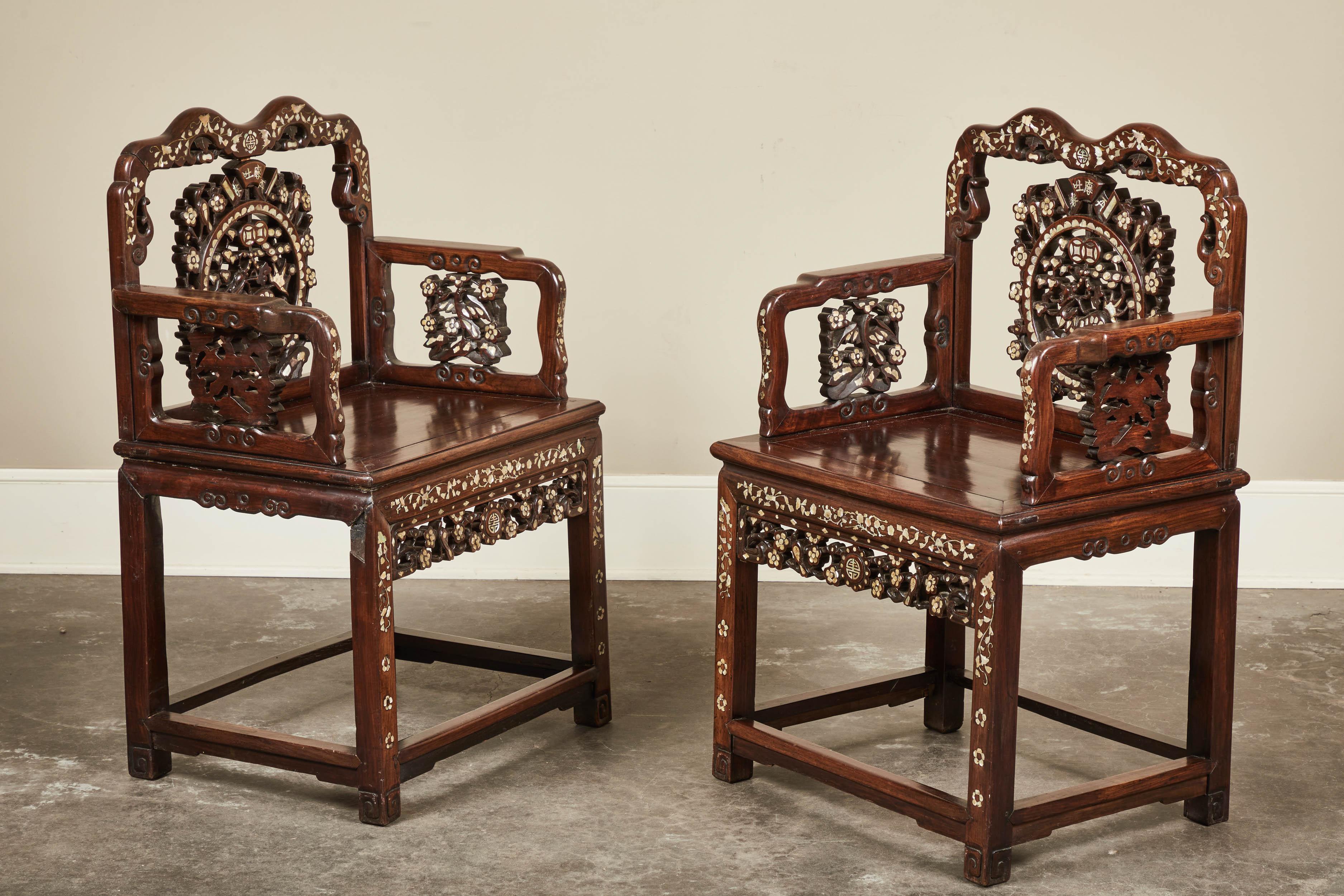 A pair of 19th century Chinese mother of pearl inlaid rosewood chairs. Embellished arms, legs and back with an intricately carved splat. Sold as a pair.