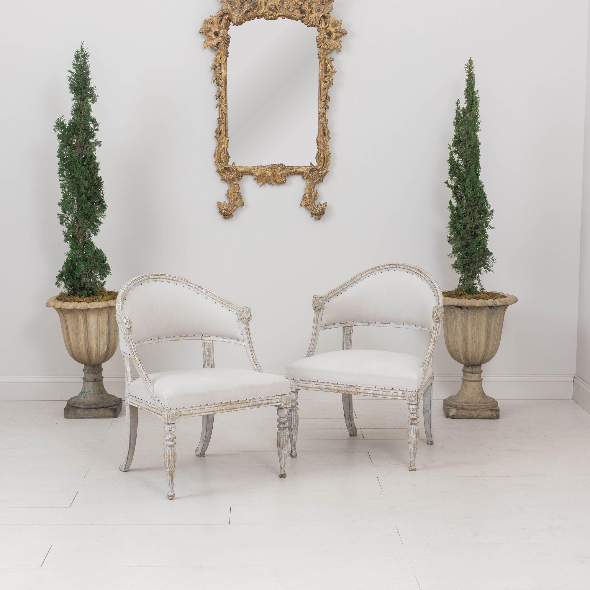 Zwei antike schwedische Sessel im Gustavianischen Stil, um 1880. Diese herrlichen Stühle haben eine geformte Rückenlehne mit geschnitzten Löwenköpfen. Der Rahmen weist geschnitzte Glockenblumen auf, die Vorderbeine sind mit Lotosblumen und Rosetten