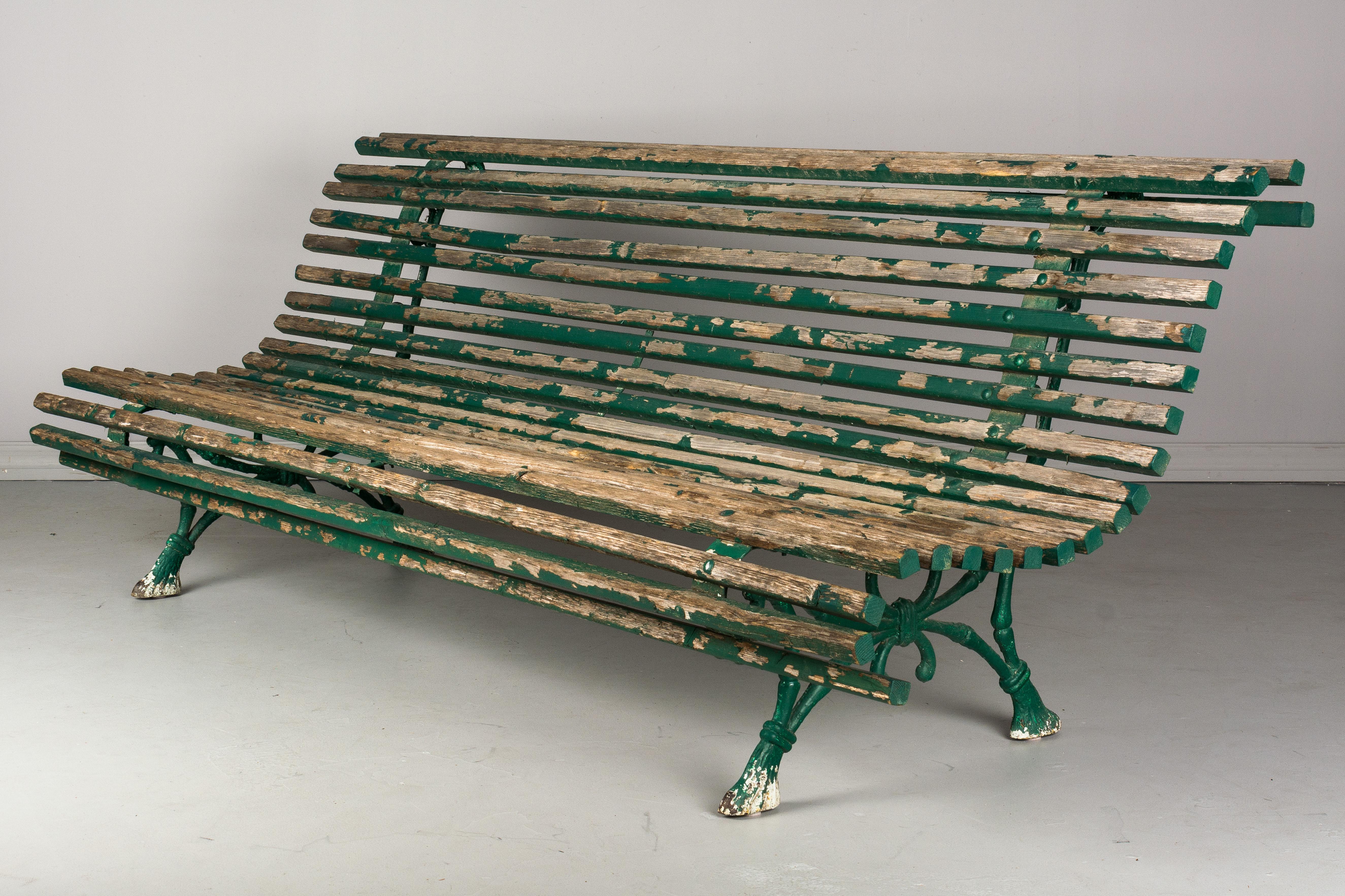 A 19th century French garden bench from a park in Paris. Green painted cast iron base with oak slats. Nice quality iron work and good sturdy condition. Old peeling paint is as found.