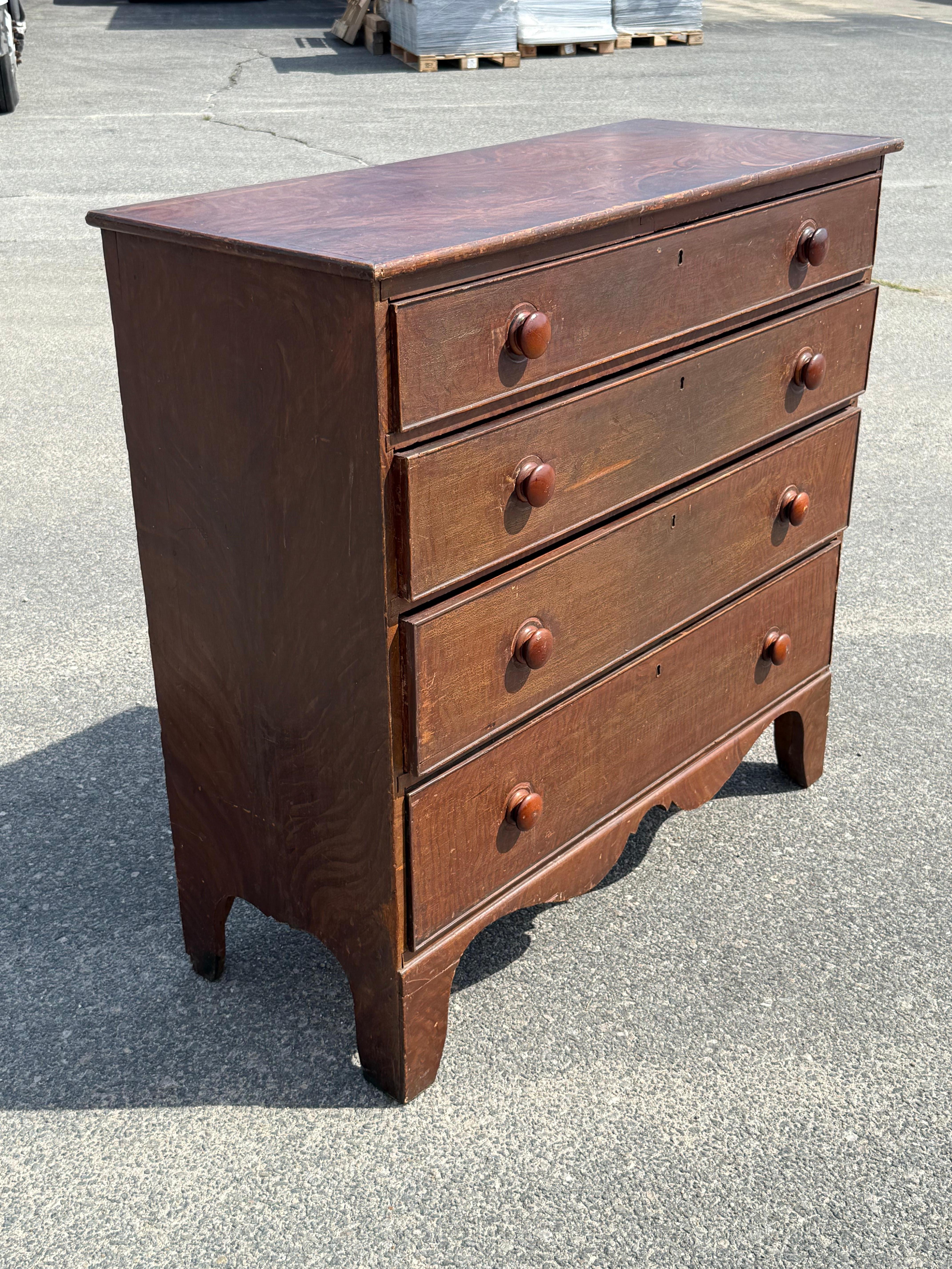 19th century pine chest of four graduated, beaded drawers.  Original grain painted surface with craquelure.  Turned knobs and shaped skirt.  Nova Scotia.