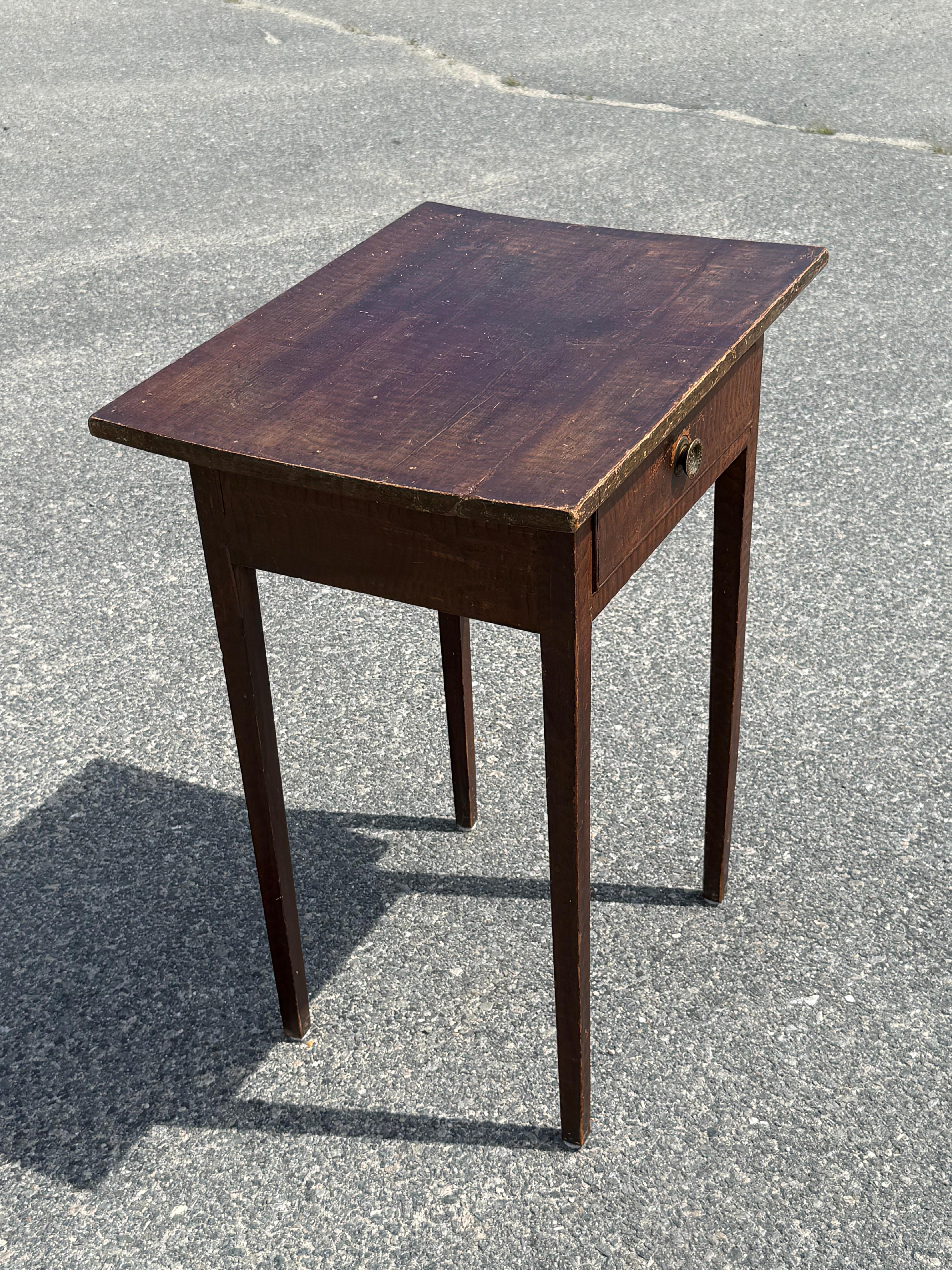 19th c. Pine one drawer stand with original faux tiger maple decorated paint.  Slightly bowed single board top over drawer with brass pull, terminating on lightly tapered legs. Quebec. 