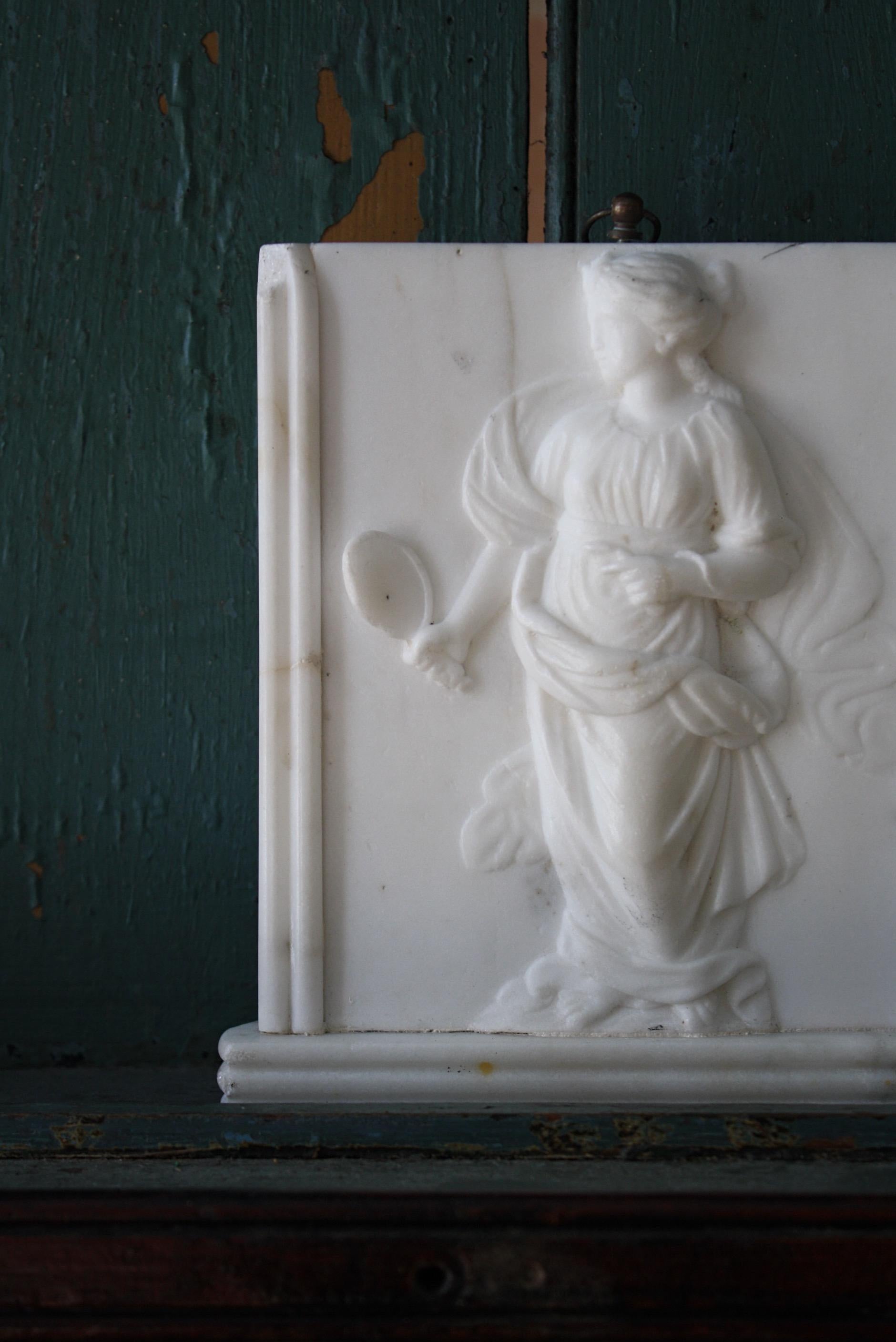 A finely carved pair of early 19th century marble tablets depicting the goddess of truth Veritas and Themis the goddess of justice once part off a fire surround.

Later hanging hoops added, age related wear and discolouration. 

Very much in the