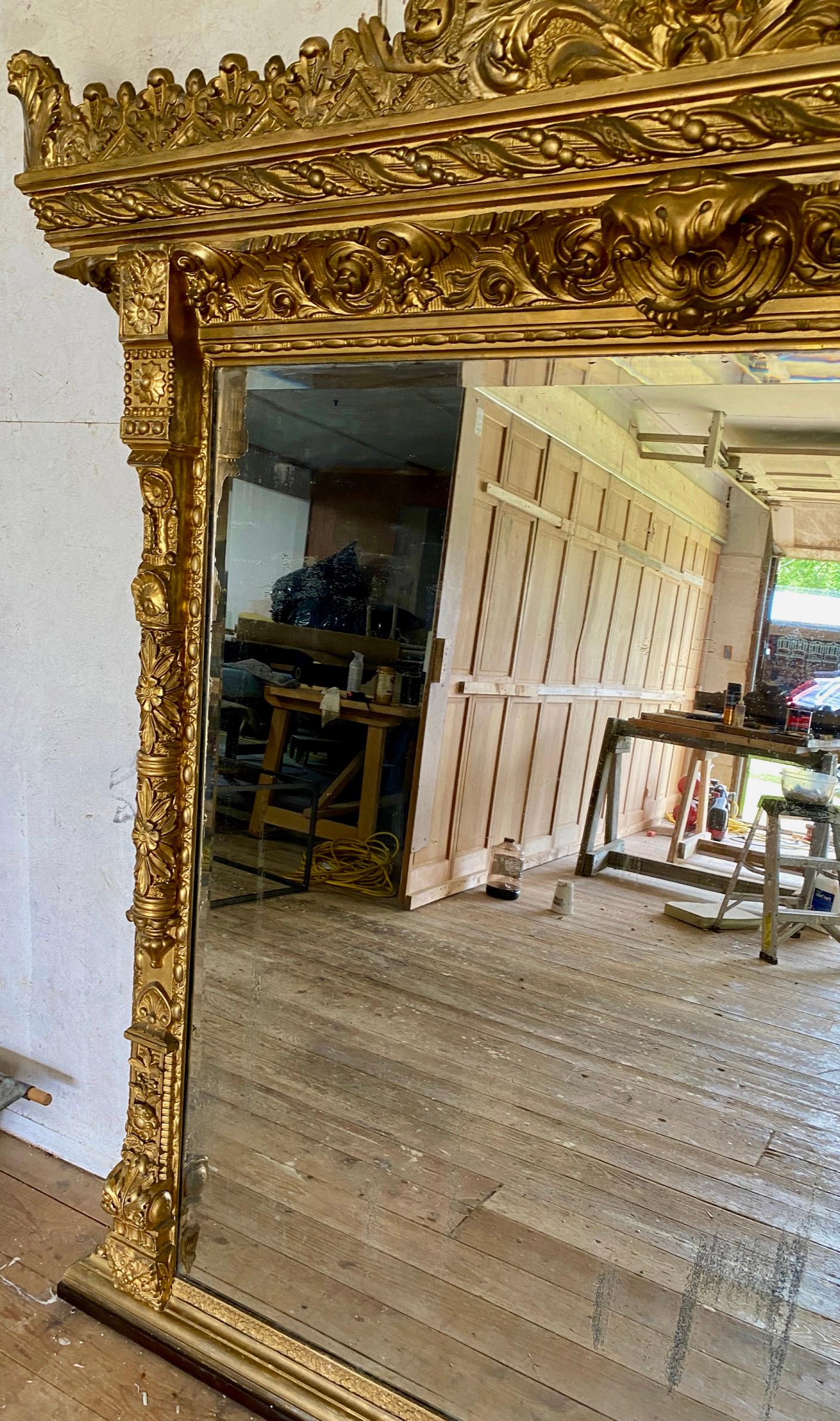 Impressive monumental scale antique Italian rectangular mantel or fireplace mirror. The piece has two bold pillars with highly detailed carved molding all the way around. The Italian Renaissance revival trompe l'oeil mirror with lovely antique