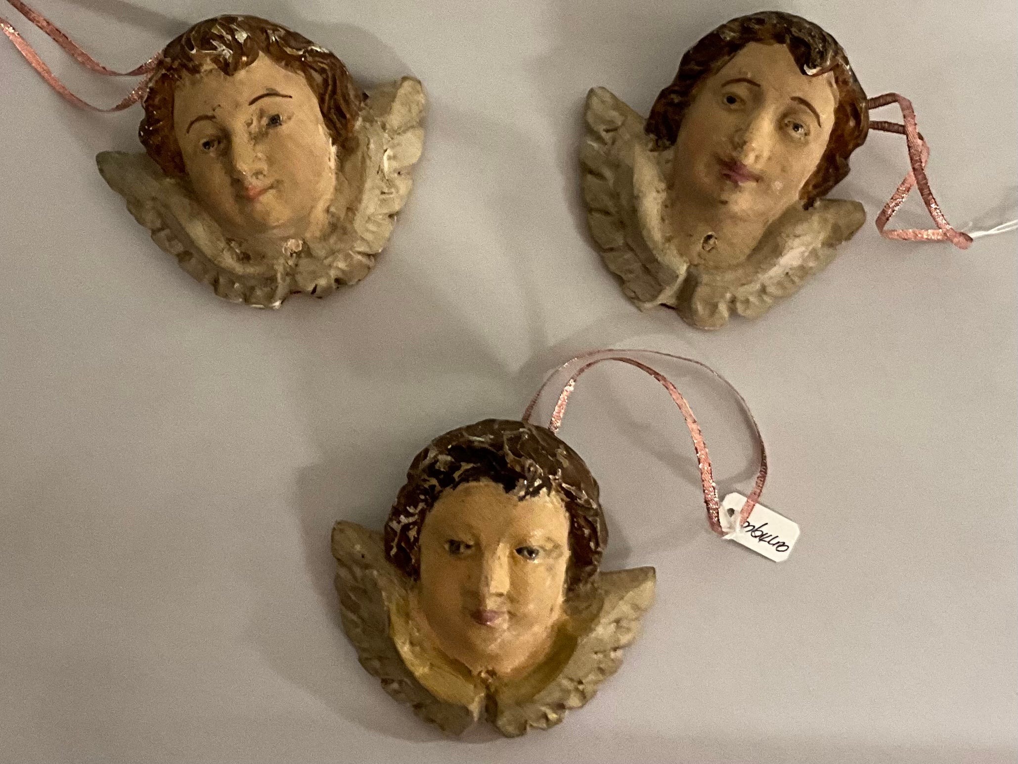 This is a set of three 19th century Rococo style carved puttis that have been modified into holiday ornaments. They are hand painted and show some age appropriate wear. Many of the little eyes are glass.