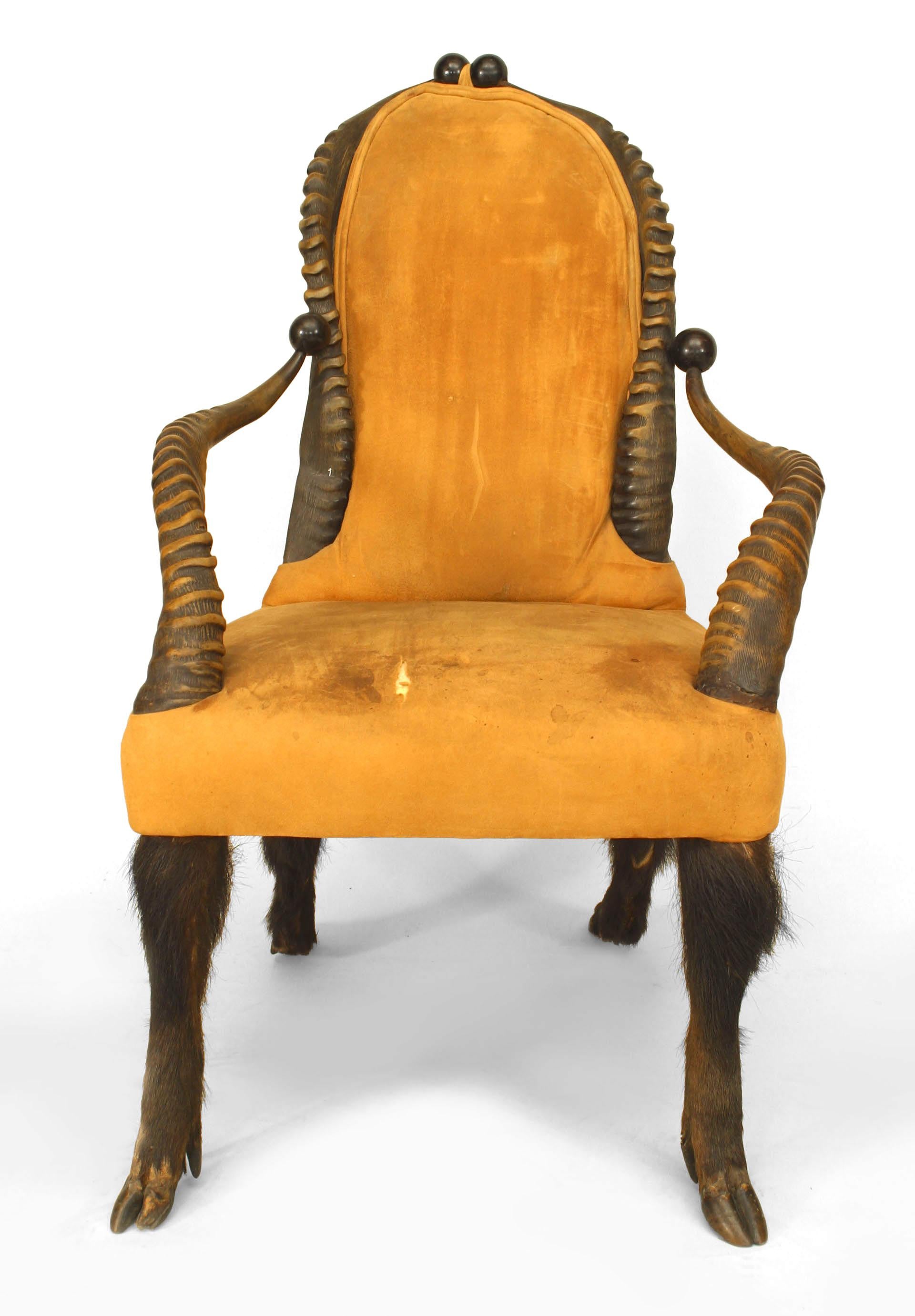 Rustic arm chair featuring ribbed antler arms and back, beige suede upholstery, black ball trim, and four hairy legs with hoof feet. Of possible South African origin.