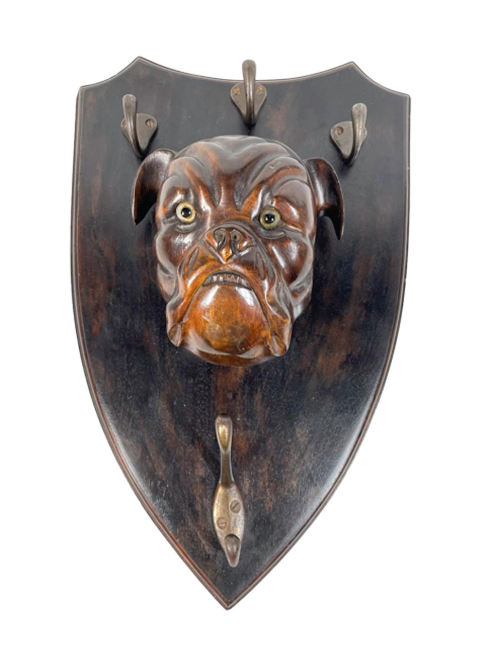 19th Century lead / leash hanger of shield form having a carved wood bulldog head with glass eyes below 3 single hooks and above a double hook.