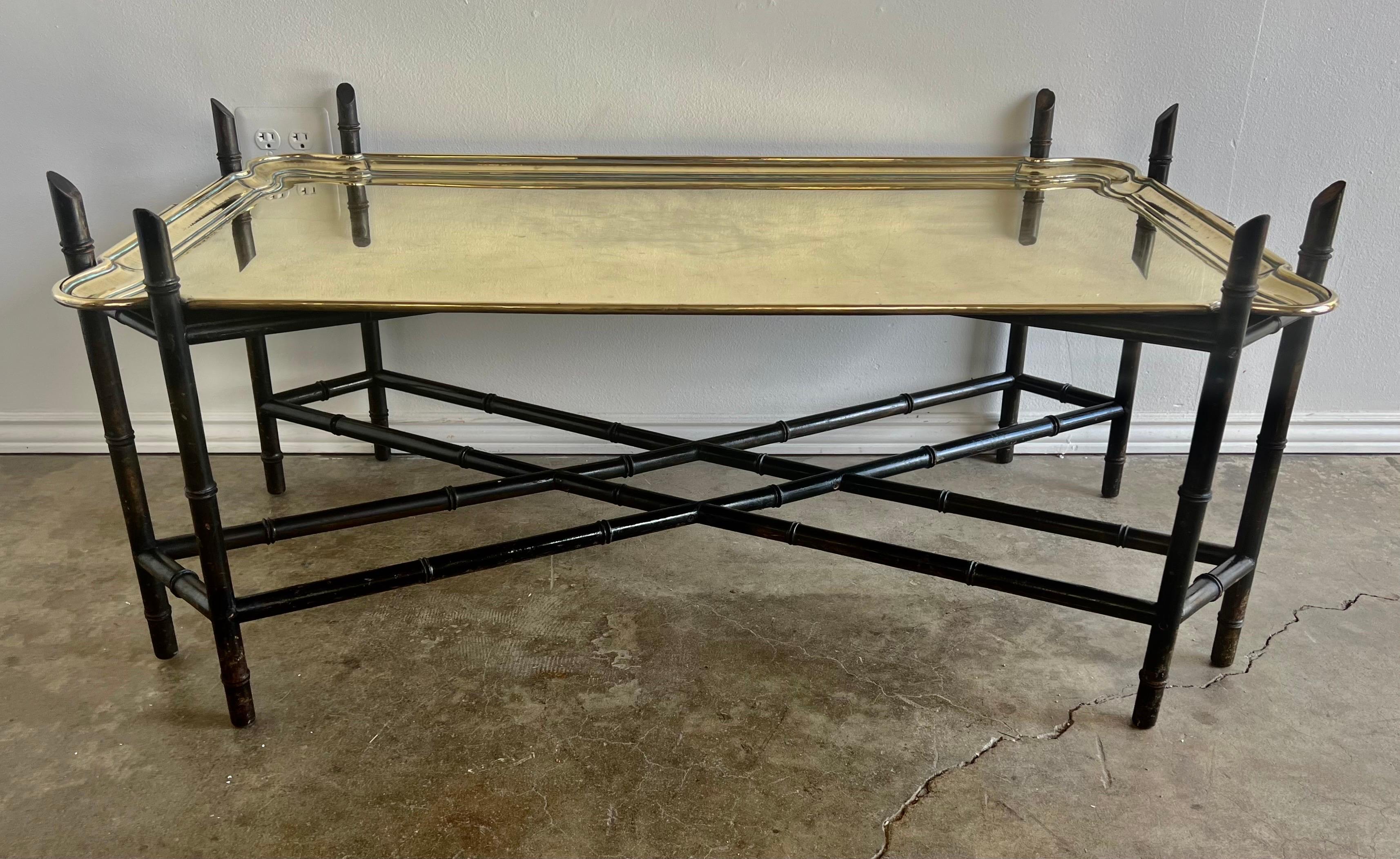 Early 20th century solid brass tray table. The brass tray sits on a carved wood chinoiserie style base with a bottom stretcher.. The base is painted black. The two handled monumental tray is stamped 