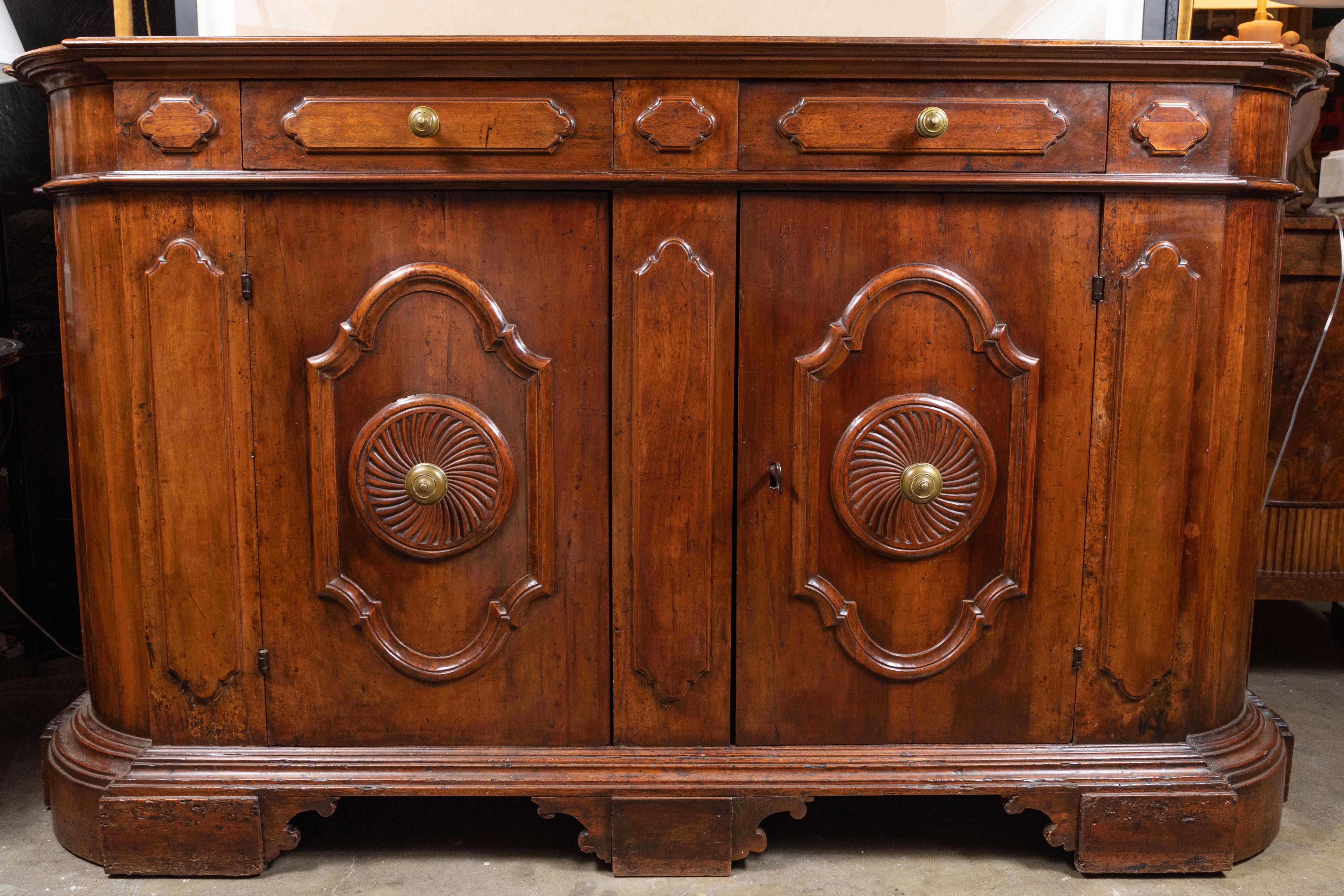 Stately, two-over-two, 1850s, hand carved, rounded edge, solid walnut buffet on a raised, stepped base of the same. The whole generously worked with both raised, and recessed panels. The newer, gilt bronze doorknobs are centered in elegant, whirled