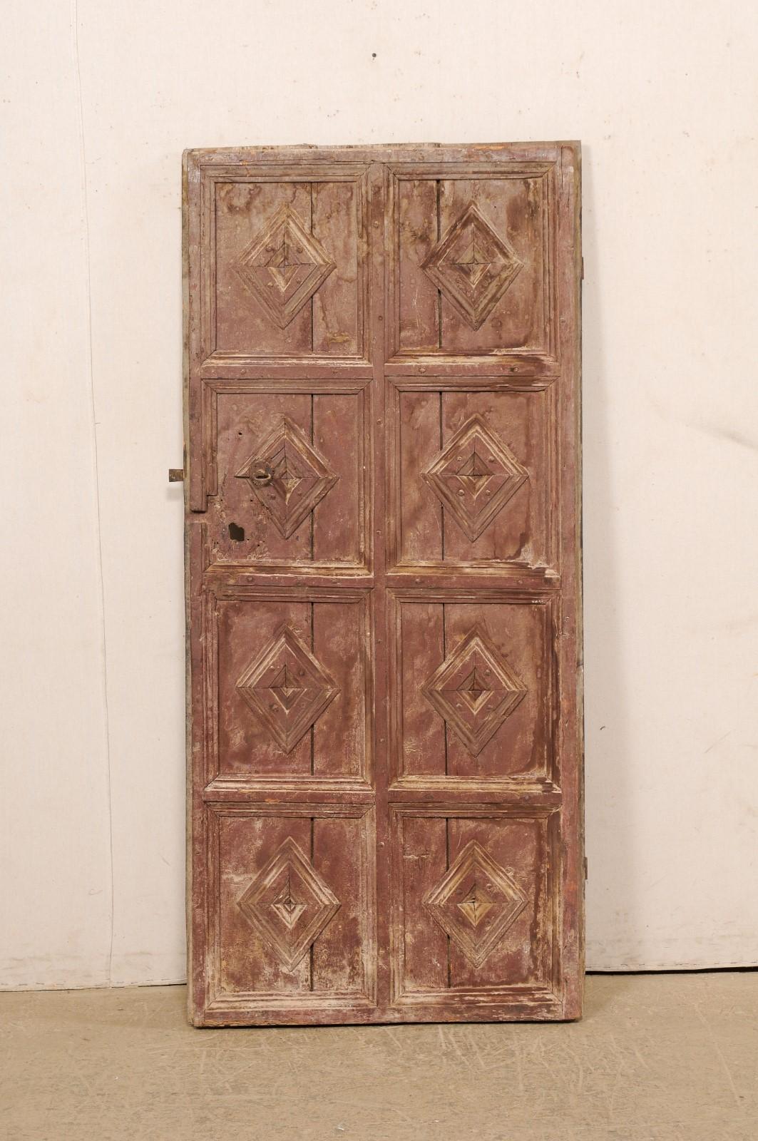 A Spanish painted eight panel wood door, with decorative diamond motif, from the 19th century. This beautifully-rustic antique door from Spain has been designed with eight squared raised panels, each embellished with raised diamond patterns within
