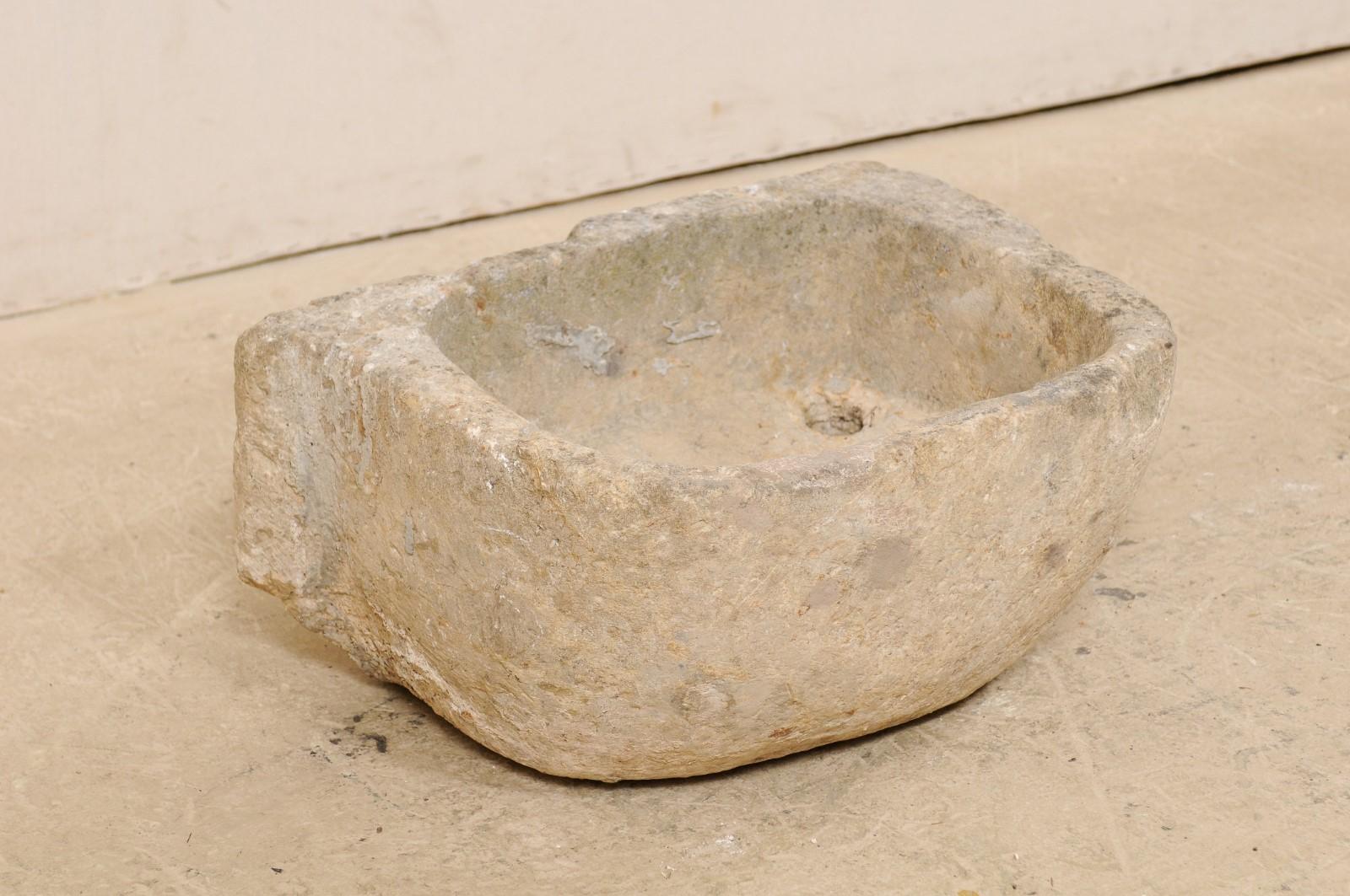 A Spanish limestone sink basin from the 19th century, possibly older. This antique hand carved limestone sink from Spain has a rounded front with flat backside, giving it an overall 