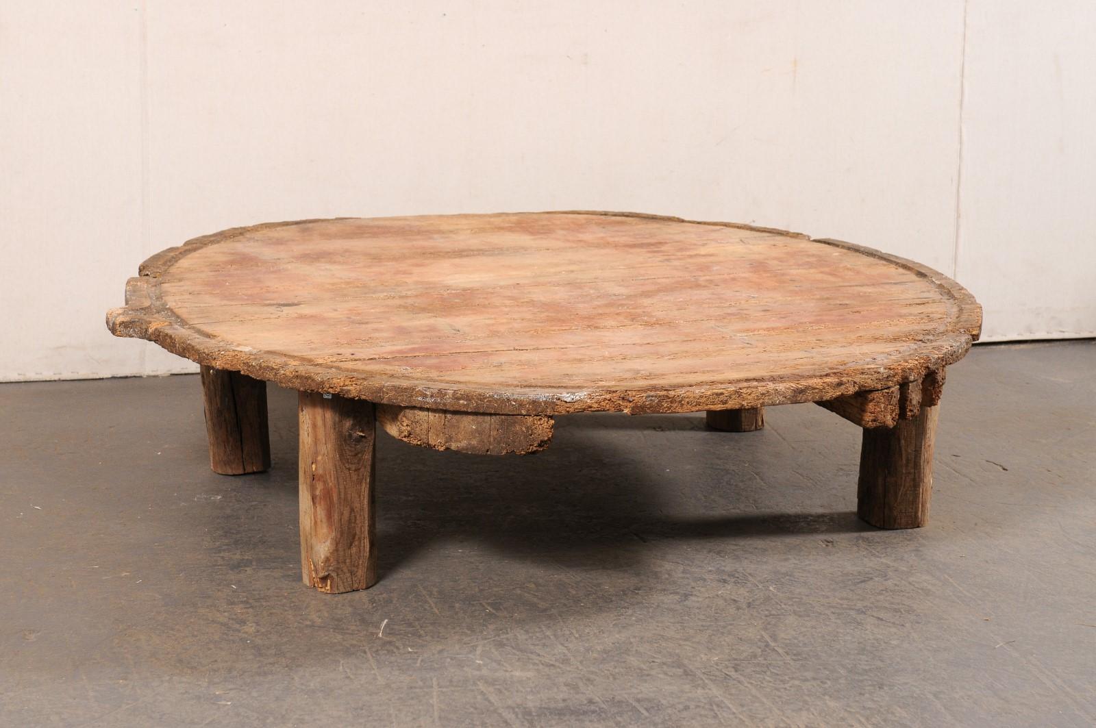 This large-sized coffee table has been created from a 19th century Spanish olive-press barrel. It features a live-edge and round-shaped top, just over 5 feet in diameter, with the original hand-carved spout/pour at one side, and the notched/carved