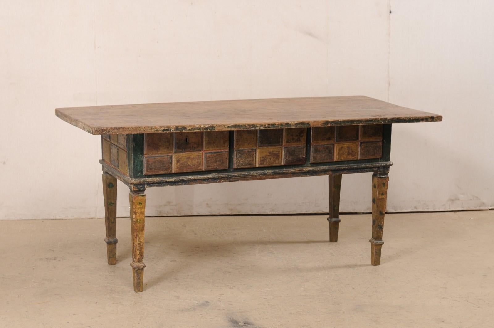 A Spanish carved and painted wood table with drawers from the 19th century (possibly older). This antique table from Spain is very unique and quite lovely with its rustic wood top which overhangs a deeply set apron adorn on all sides in carved
