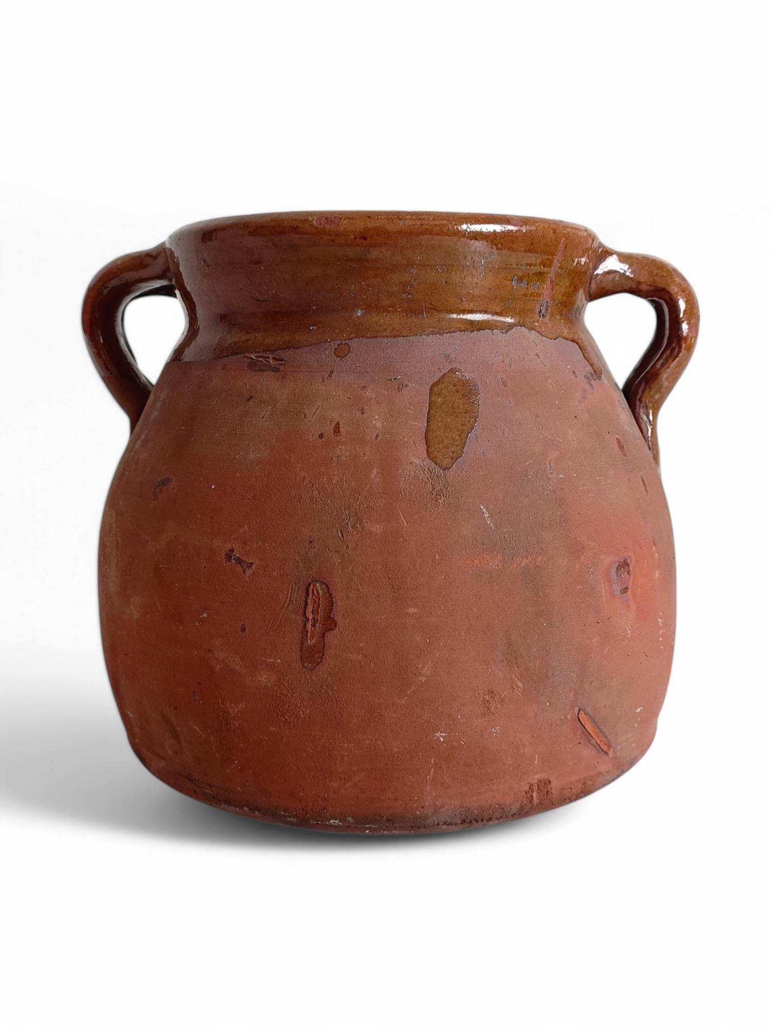 Olla de cuisine traditionnelle à double poignée en terre cuite, à la patine riche et vieillie. L'extérieur présente une finition en terre cuite brute et mate, tandis que le bord et l'intérieur sont émaillés, ce qui permet de cuisiner sur un feu