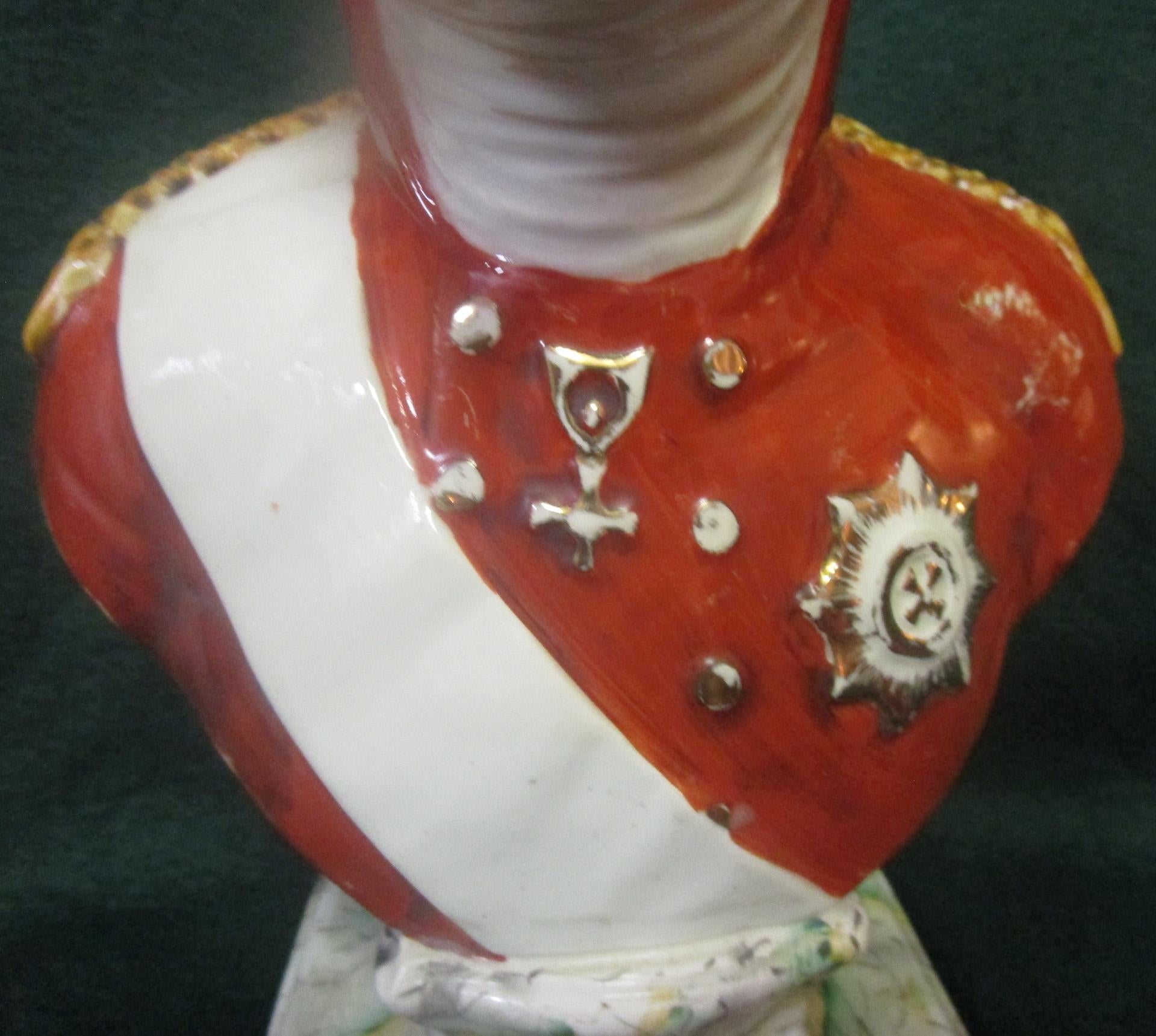 This handsome hand-painted English Staffordshire pottery bust of Czar Alexander Ist of Russia (1796-1855) wears a modeled military uniform with white sash. The bust is turned slightly to the right and sits upon a modeled waisted plinth with faux