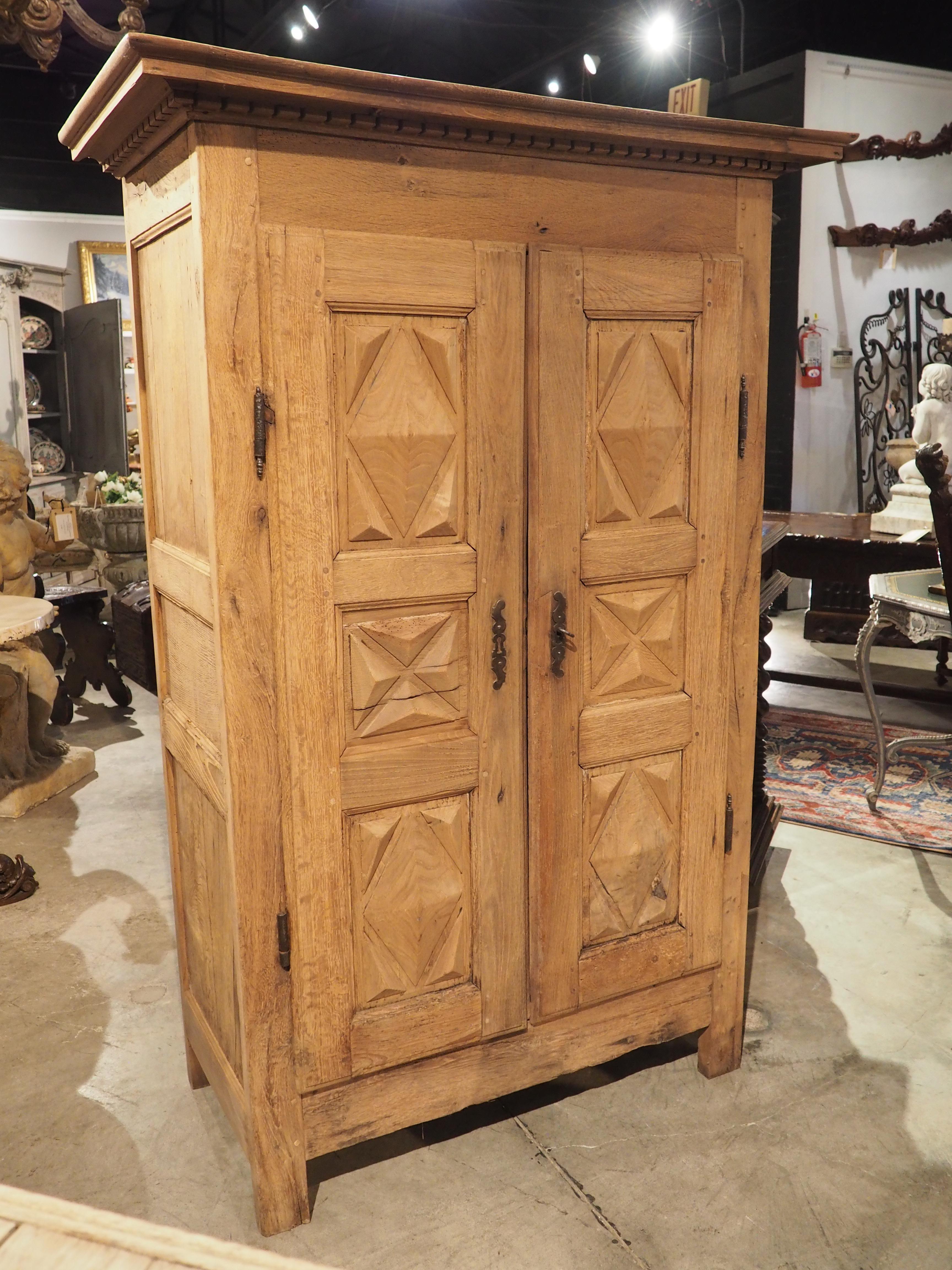 This unique armoire was hand-carved from oak and chestnut wood in Brittany, France, during the 1800’s. Carved in the Louis XIII style (notice the geometric shaped moldings), the two motifs on the doors make this a rare find, as typically ebenistes