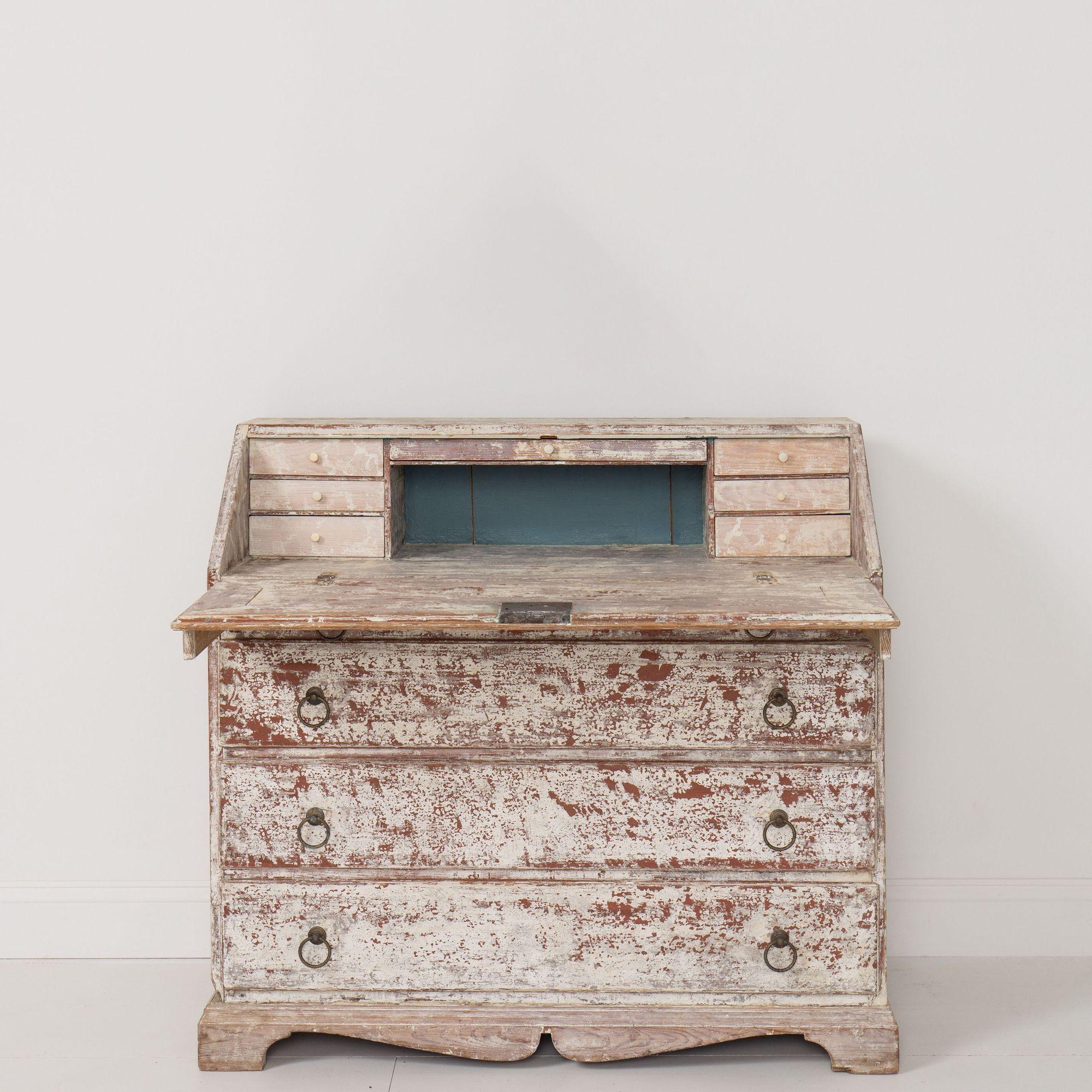 A Swedish bureau secretary with a scalloped base in original paint. Circa 1870. Behind the drop-down desk there are three graduated drawers on either side of a center pigeon hole with a long drawer above. The bureau is comprised of one long, thin