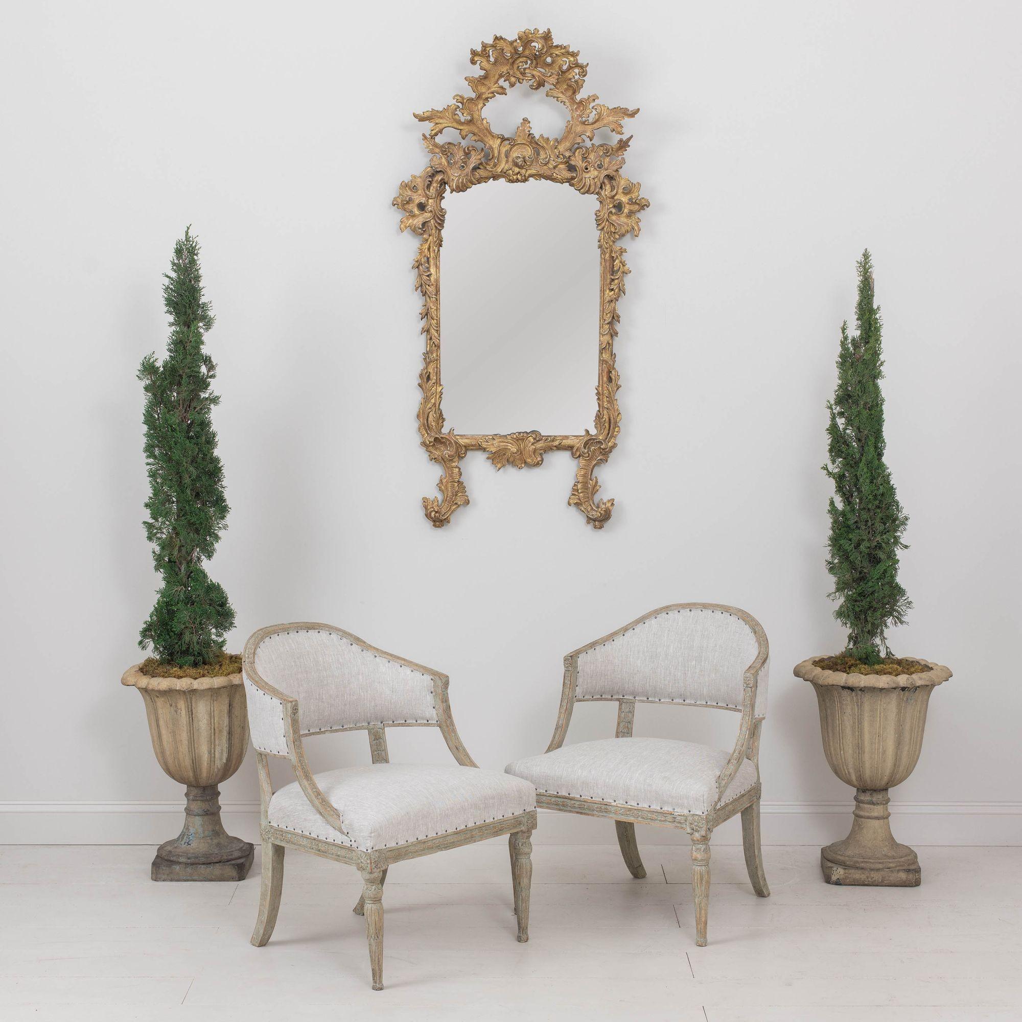A pair of Swedish antique armchairs from the Gustavian period, circa 1810. These stunning chairs have shaped barrel backs. The frame features carved bell flowers with front legs adorned with lotus flowers and rosettes. This pair has been newly