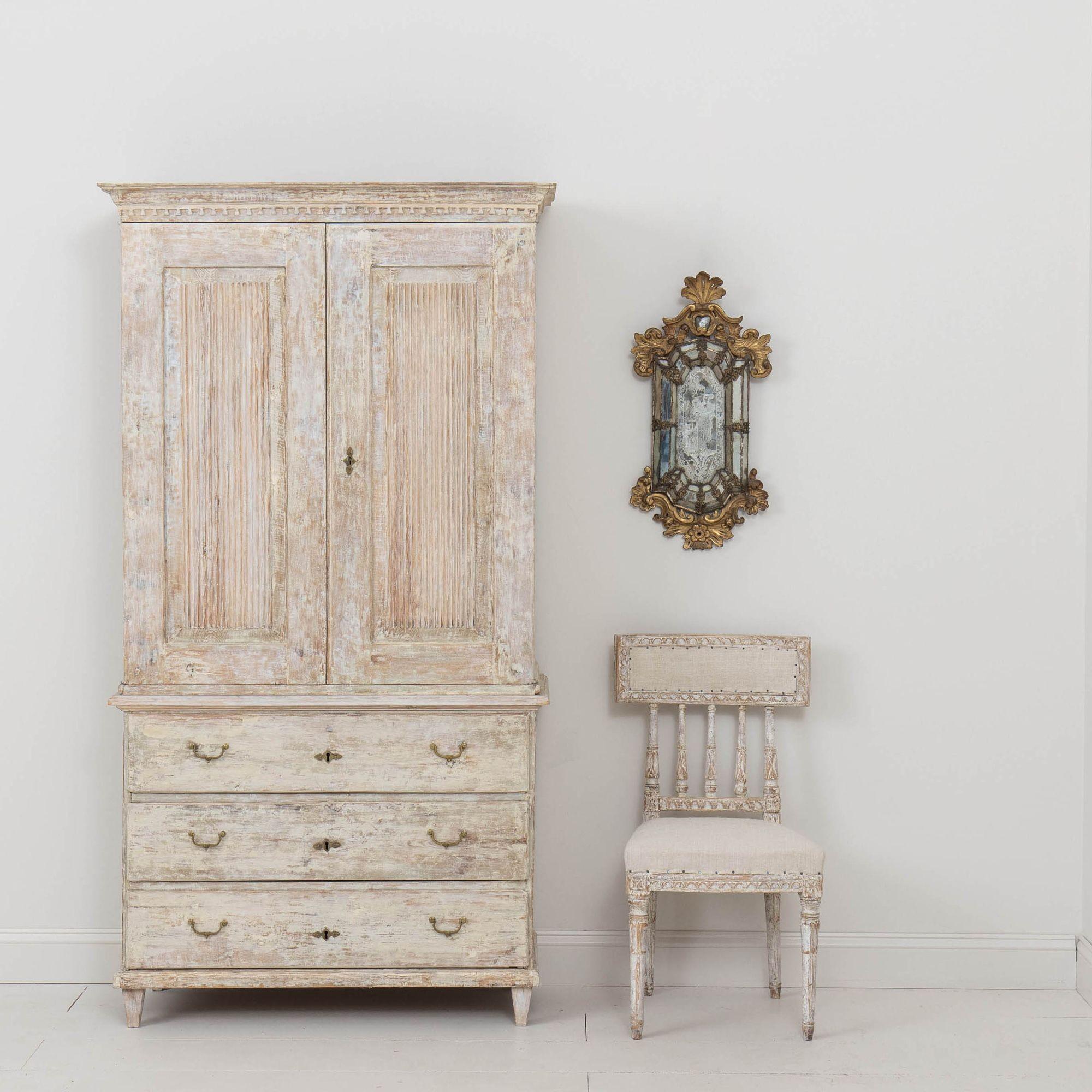 A 19th century Swedish Gustavian period cabinet from Stockholm dry scraped back to reveal the original paint and natural wood surface. Circa 1810. This beautiful cabinet has beautifully carved molding around the top, two large reeded doors above