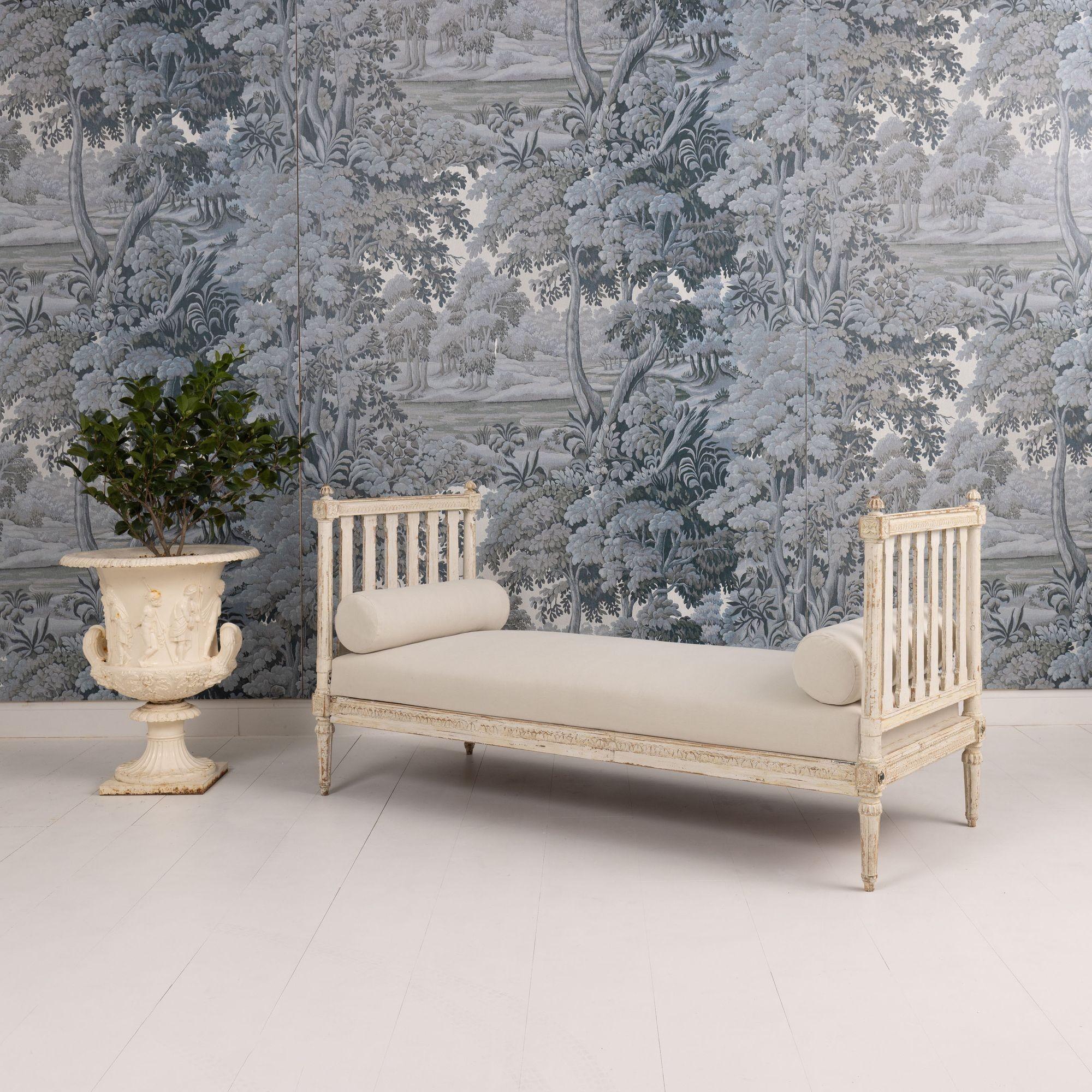 A striking 19th century Swedish Gustavian period daybed, circa 1800. This piece has been hand-scraped to reveal the original paint surface. Finials above rosettes on the arms. Beautiful leaf tip carved detail around the arms and three sides of the