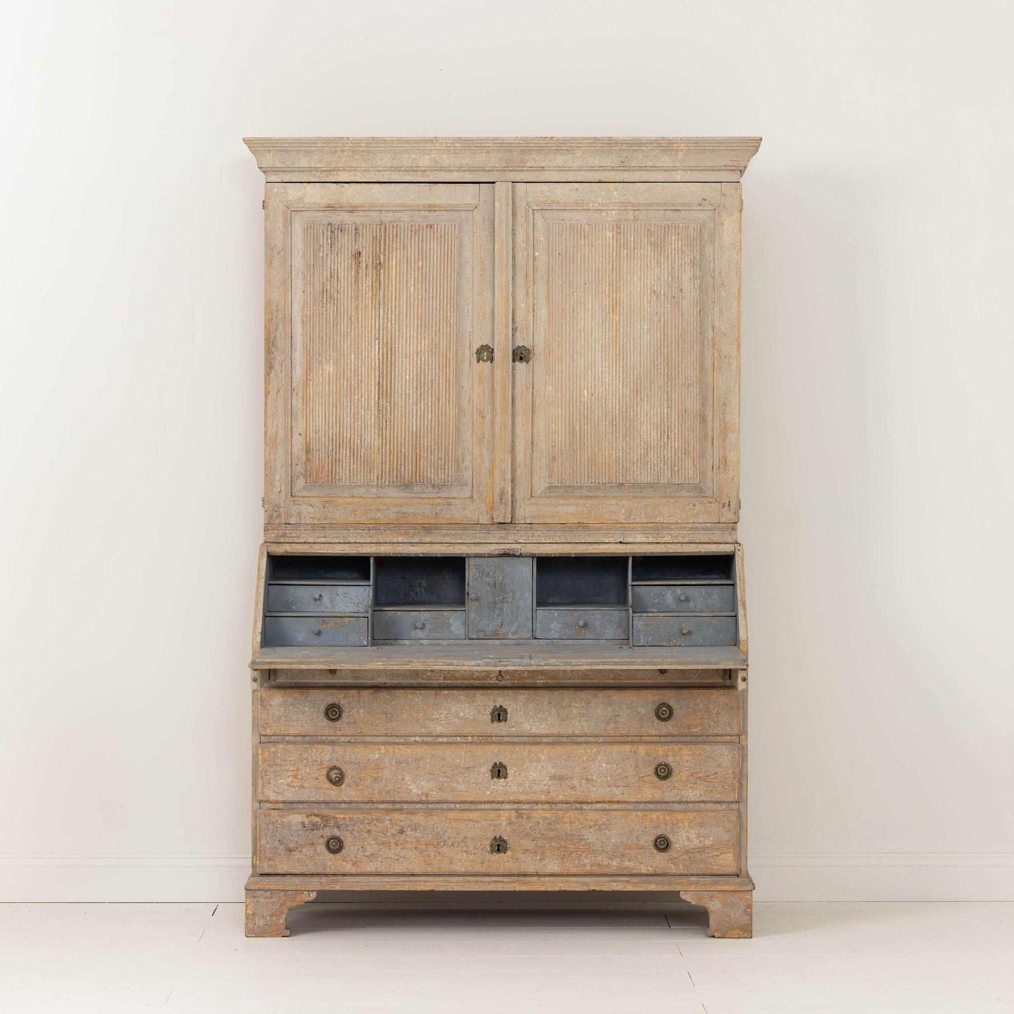 A special Swedish Gustavian period painted secretary with library, circa 1810. The upper section has two shelves, behind large reeded doors. The lower section has a slant front with three graduated drawers on either side of a center door all behind