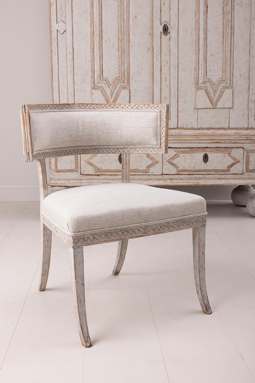 An early 19th century Klismos chair from the Gustavian period, newly upholstered in linen fabric. Made in Lindome, Sweden. The Klismos design originated in ancient Greece. The model is known for its curved and concave backrest and four splayed legs.