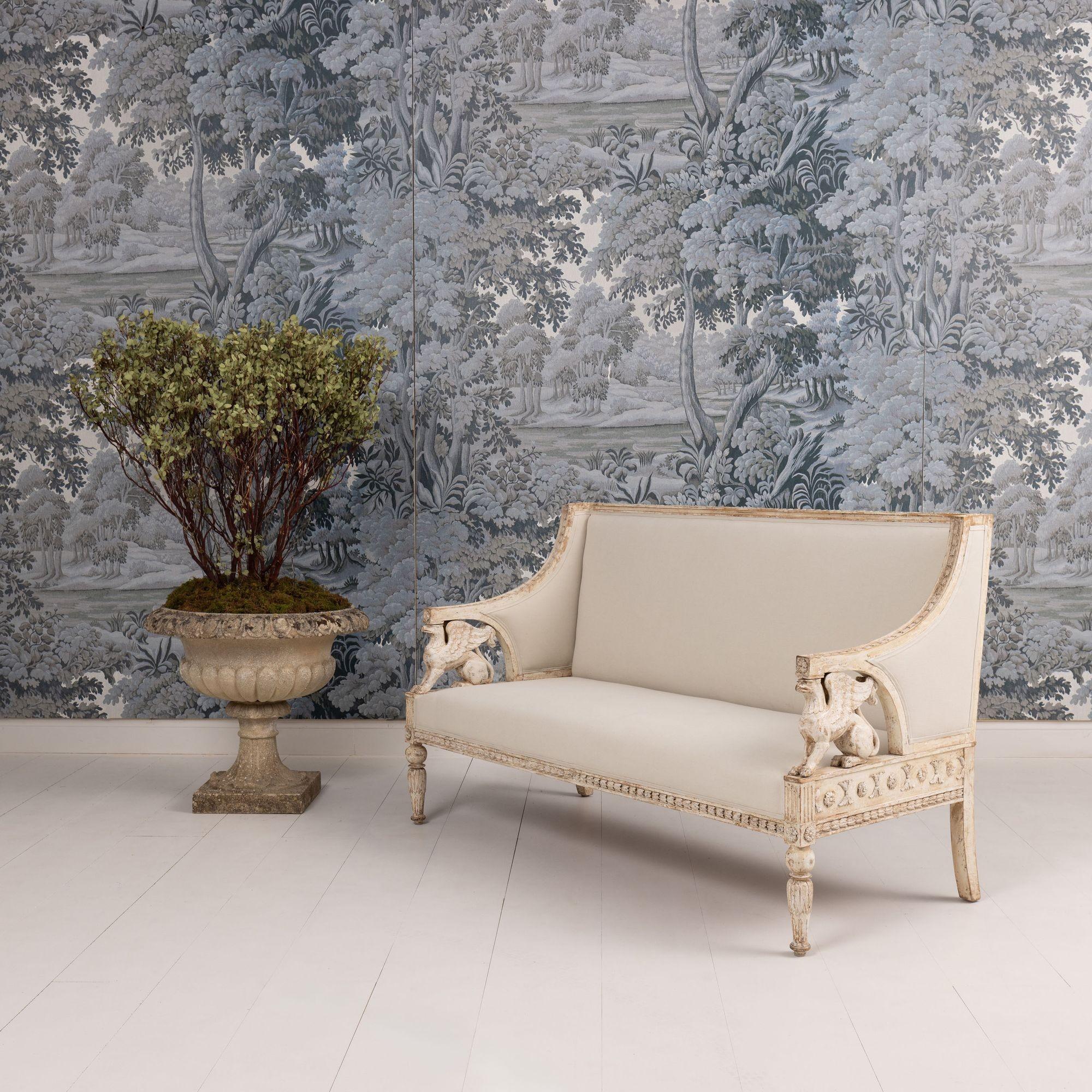 A beautiful Swedish sofa bench in the Gustavian style with carved griffins, hand-scraped to the original paint and newly upholstered in linen, circa 1880. Exquisite carved detail throughout. The back and seat frame feature bell flowers with rosettes