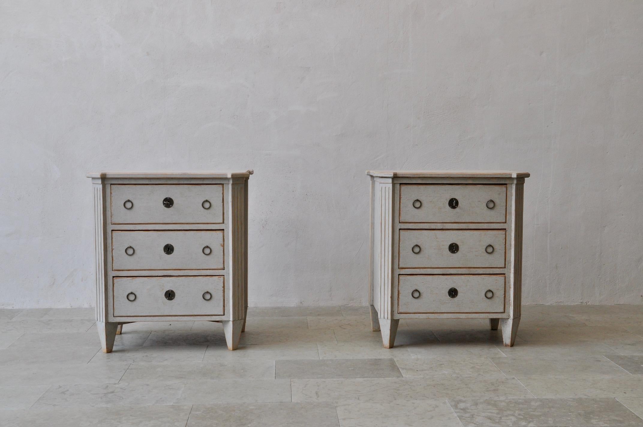 A beautiful pair of Swedish bedside chests in the Gustavian style. Three drawers, brass hardware, canted and fluted corner posts, and tapered legs. Original locks with keys.