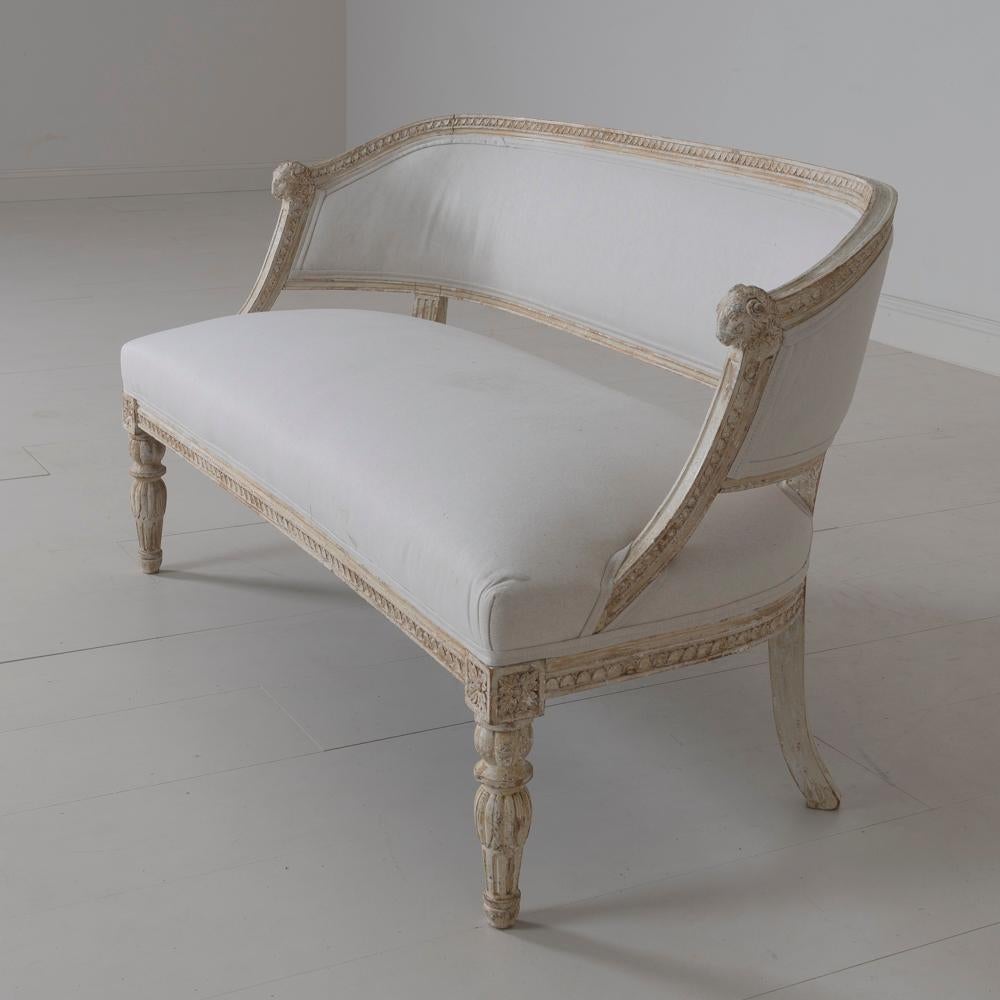 A rare 19th century Swedish barrel back sofa settee in the Gustavian style, newly upholstered in linen, circa 1880. Hand scraped to reveal the original paint. The frame has a craved egg and dart detail, while the front legs are adorned with lotus