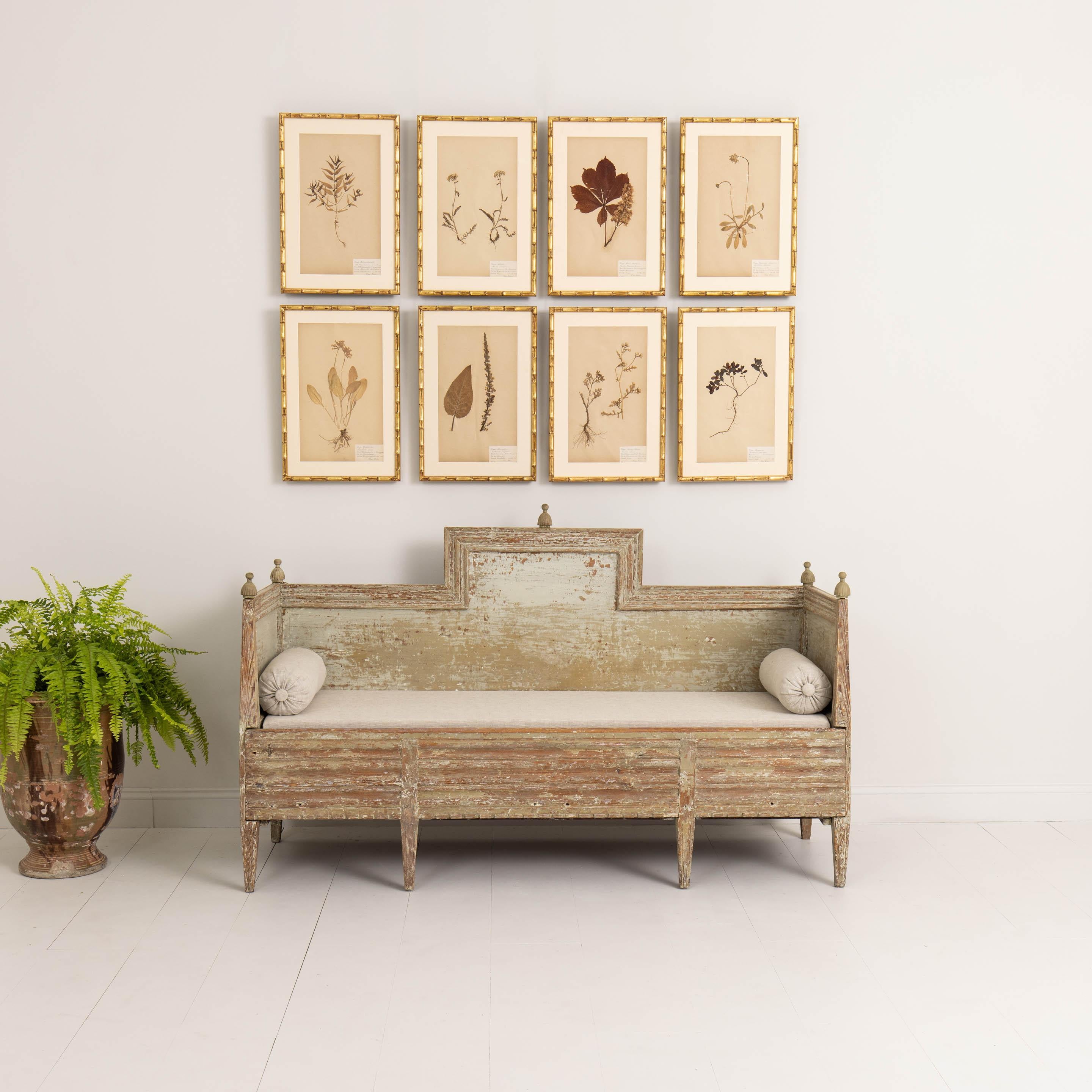 This charming 19th century Swedish Gustavian sofa or settee has been hand-scraped to reveal the original paint surface. Newly upholstered in linen with bolster pillows. This seat has the added benefit of storage under the lift-up seat. The back is
