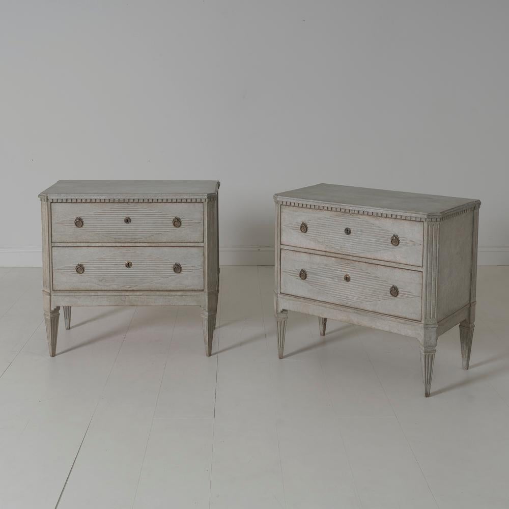 A pair of Swedish commodes in the Gustavian style. These chests have beautifully reeded drawer fronts with a lozenge design. Two large drawers, brass hardware, canted and fluted corner posts, and tapered and fluted legs. Two keys.
  