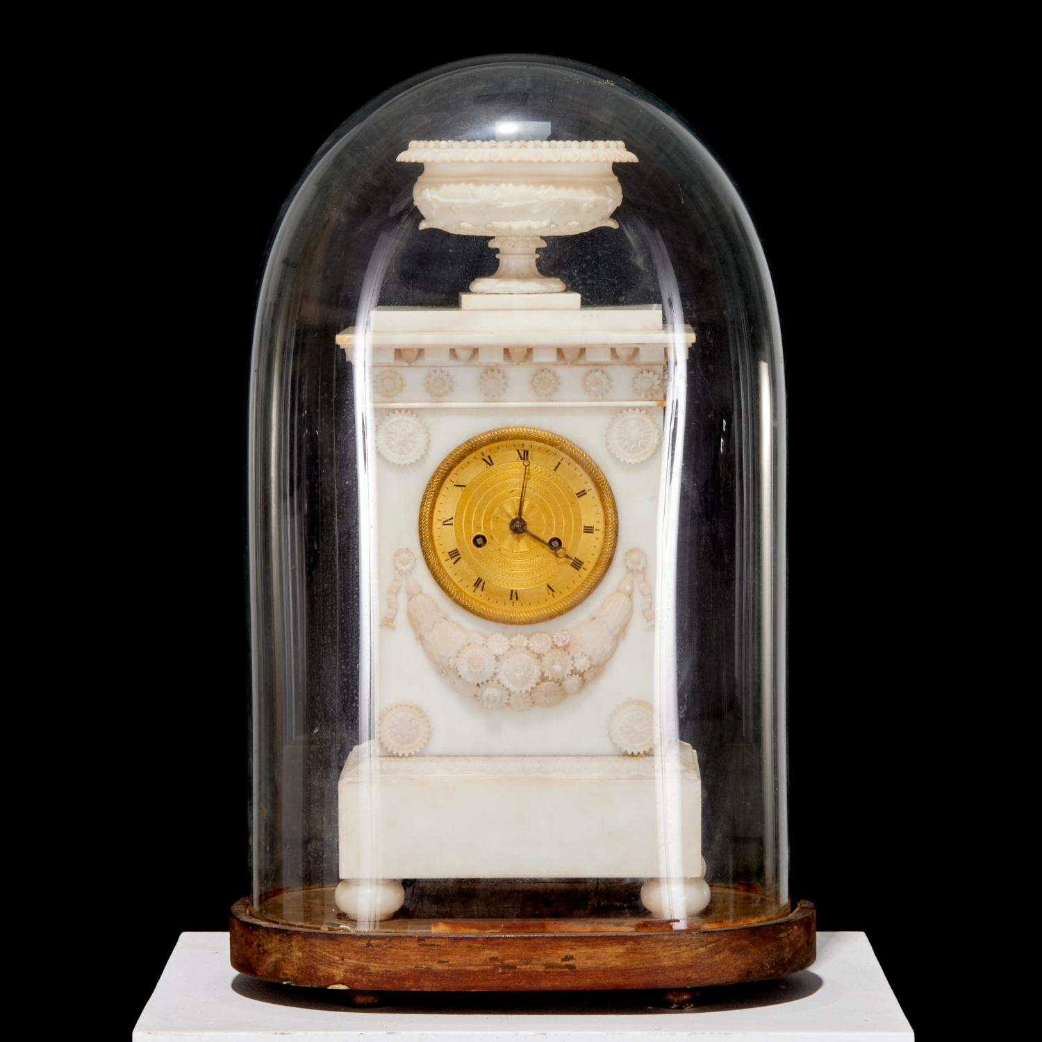 Mid 19th C, France, a highly decorative antique mantel clock enclosed under a glass dome.  The clock is made of alabaster, a material often used in neoclassical and empire-style clocks for its elegant and luxurious appearance. The clock is