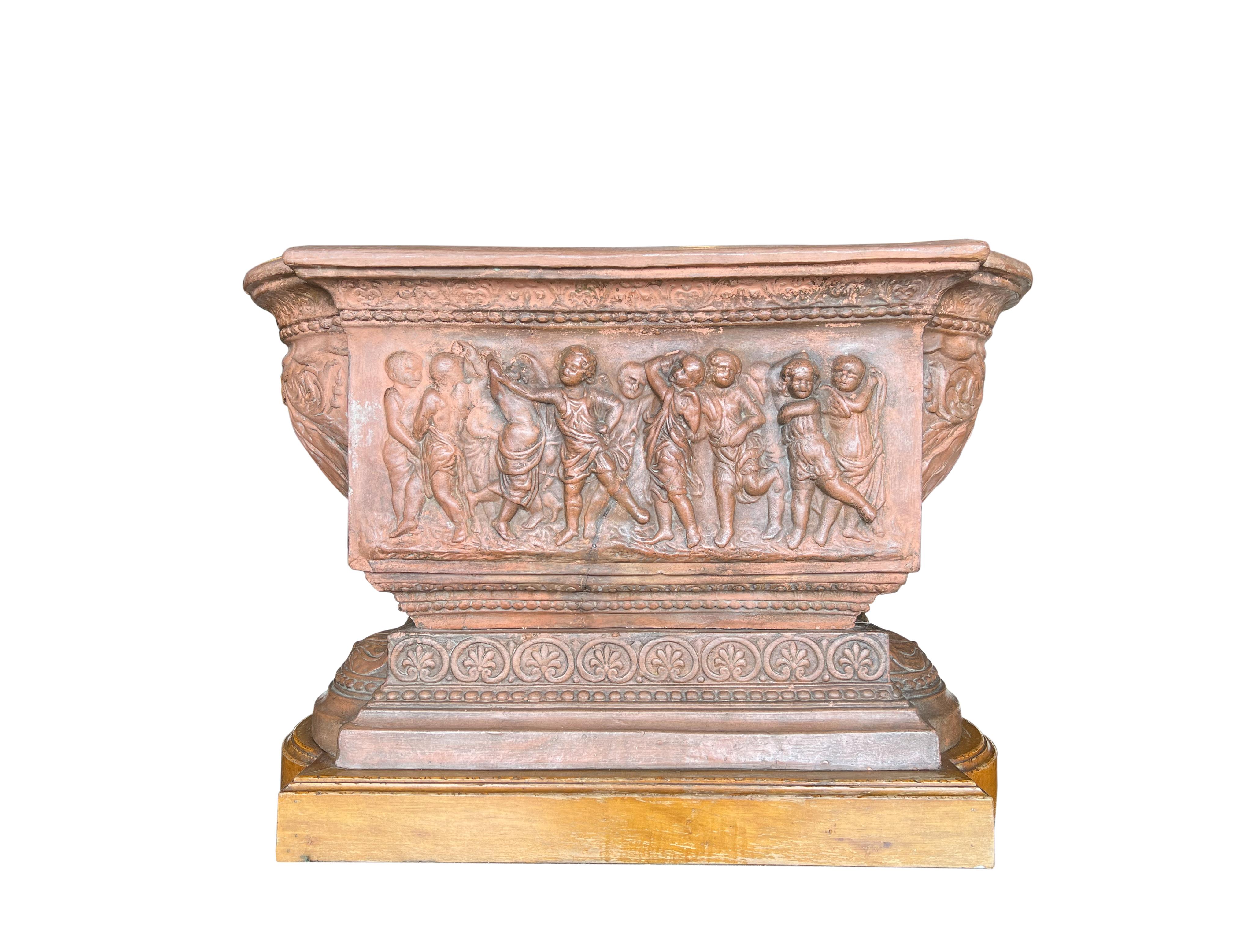 Terracotta planter centerpiece with dancing cherubs, Florence Circa 1820.

Centerpiece total measures: 27”L x 14.25”W x 18”H, including 2 pieces; the terracotta planter trough (27”L x 14.25”W x 11.25”H) which rests on the terracotta base (22”L x