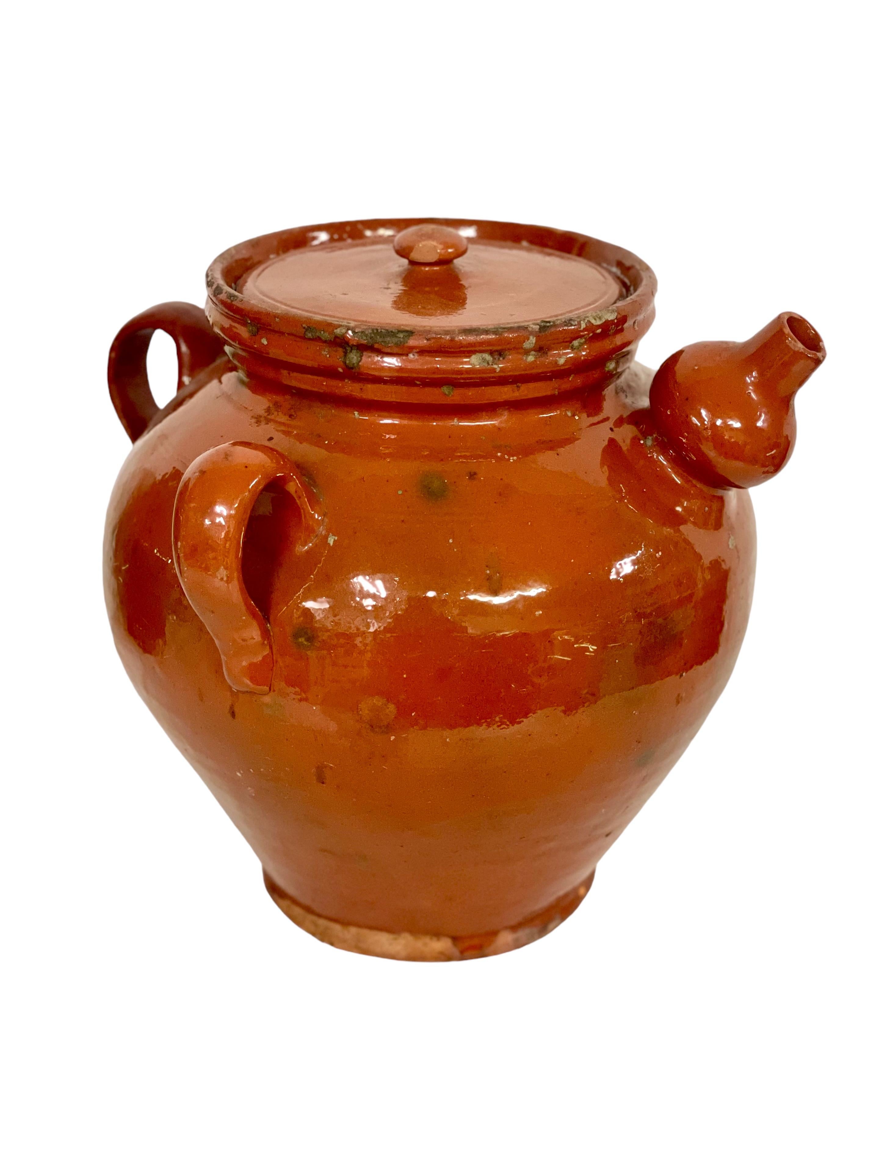 A fine French antique walnut oil jar, complete with original close-fitting lid, three side handles, and interestingly shaped spout. Originally designed for the storage and preservation of nut or olive oils, this wonderful terracotta pot with its