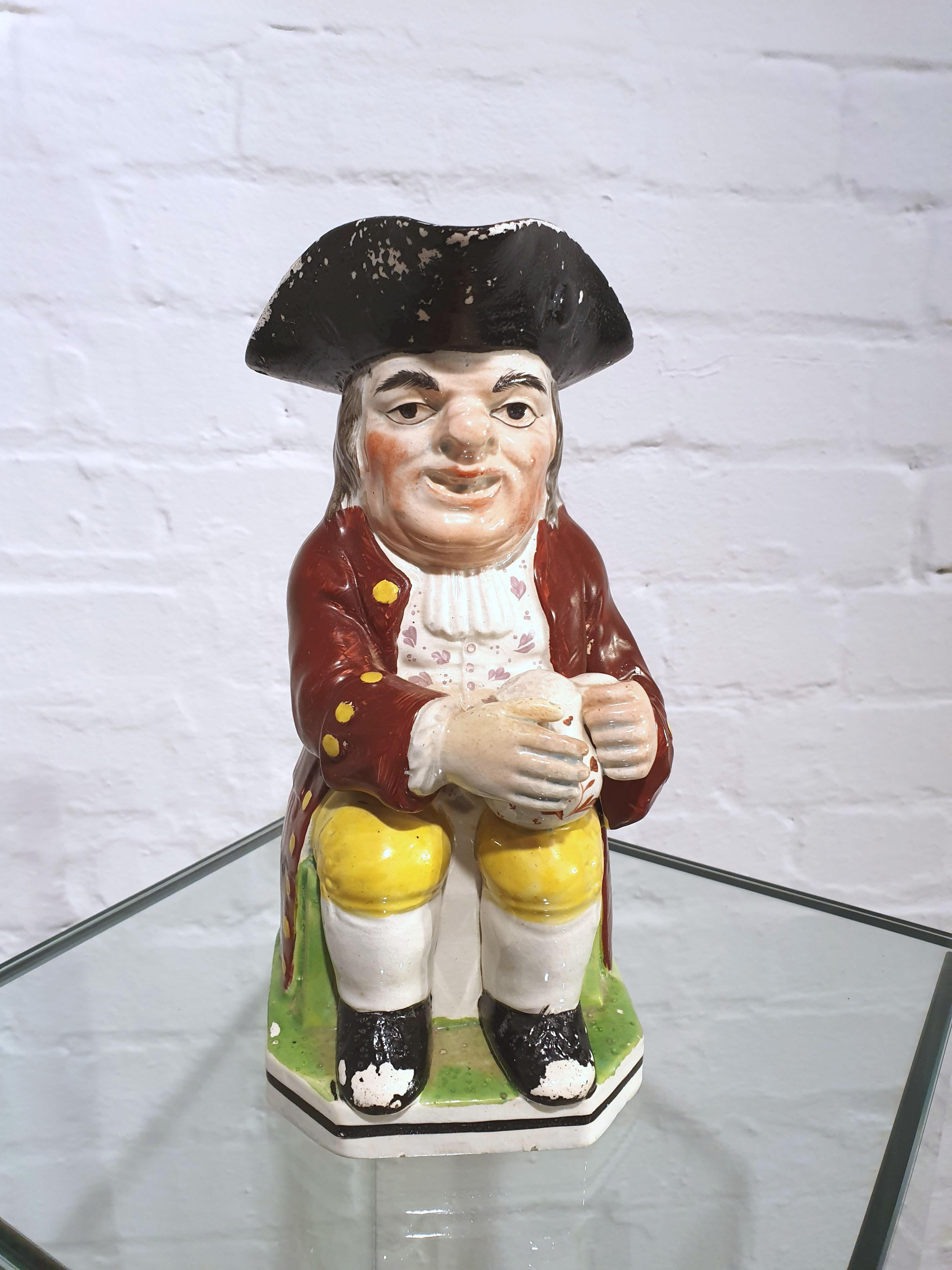 This wonderful 19th century Staffordshire pottery Toby jug is in the traditional style of a gentleman seated holding a pint wearing clothes of the period and a tricorn hat. The jug measures 5 1/8 in – 13 cm wide, 7 1/8 in – 18 cm deep and 10 ¼ in –