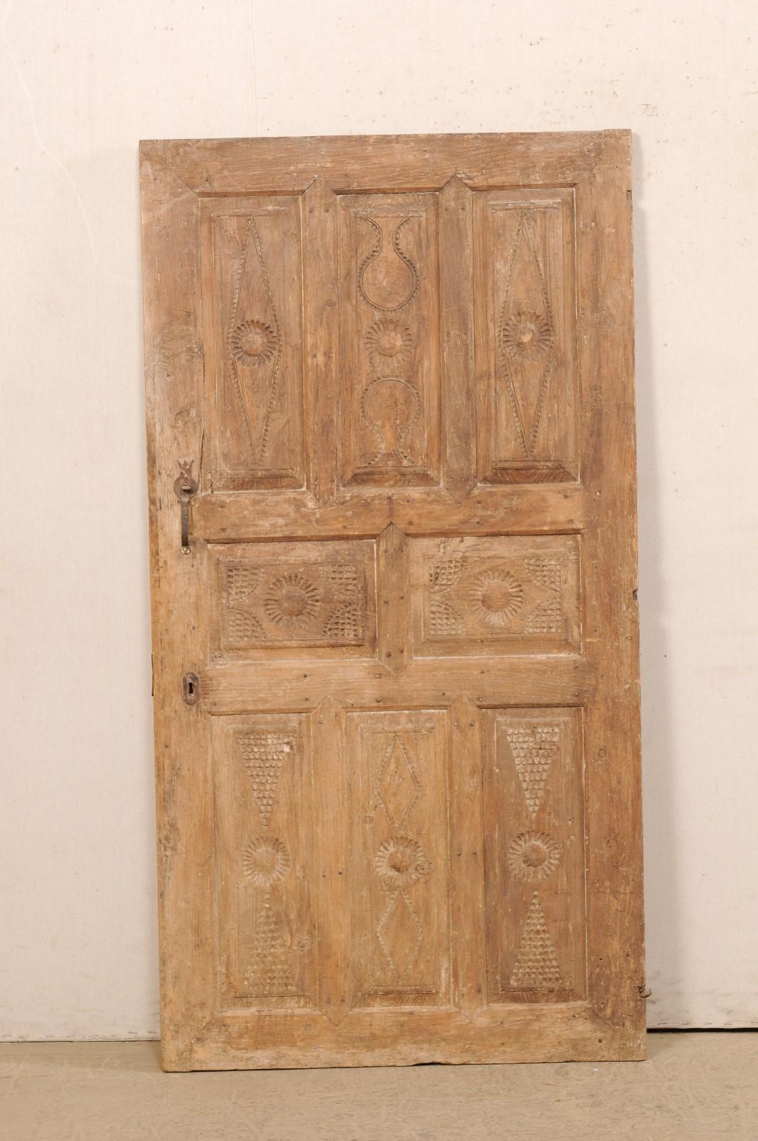 A single Turkish raised panel door from the 19th century. This antique door from Turkey has a nice 8 raised panel design on its front facade, with beautifully-rustic hand-notched geometric designs adorning each of the panels. The door is shorter