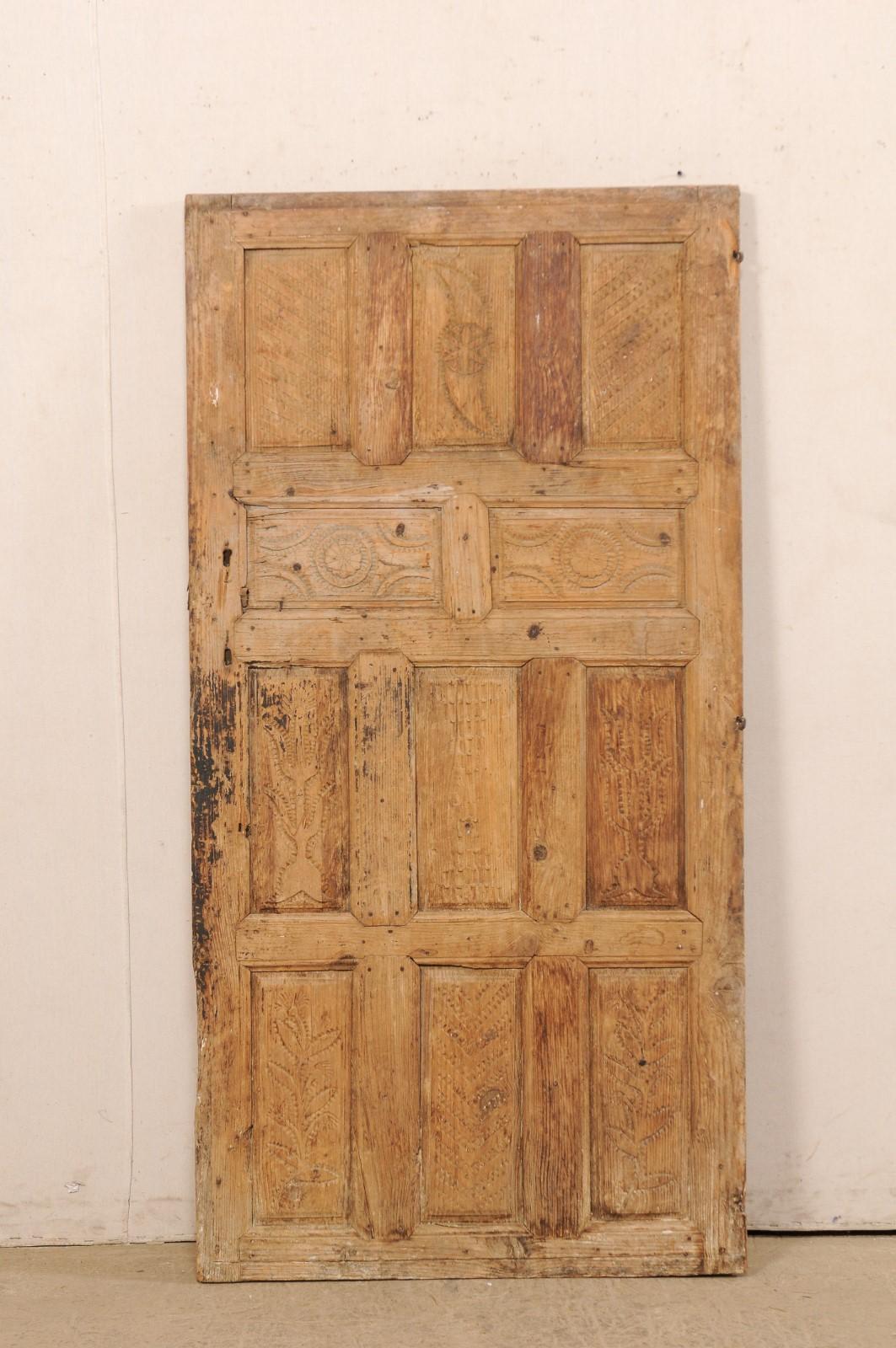 A single Turkish raised panel door from the 19th century. This antique door from Turkey has a nice 11 raised panel design on its front side, with beautifully-rustic hand-carved and notched designs adorning each of the panels. The door is shorter