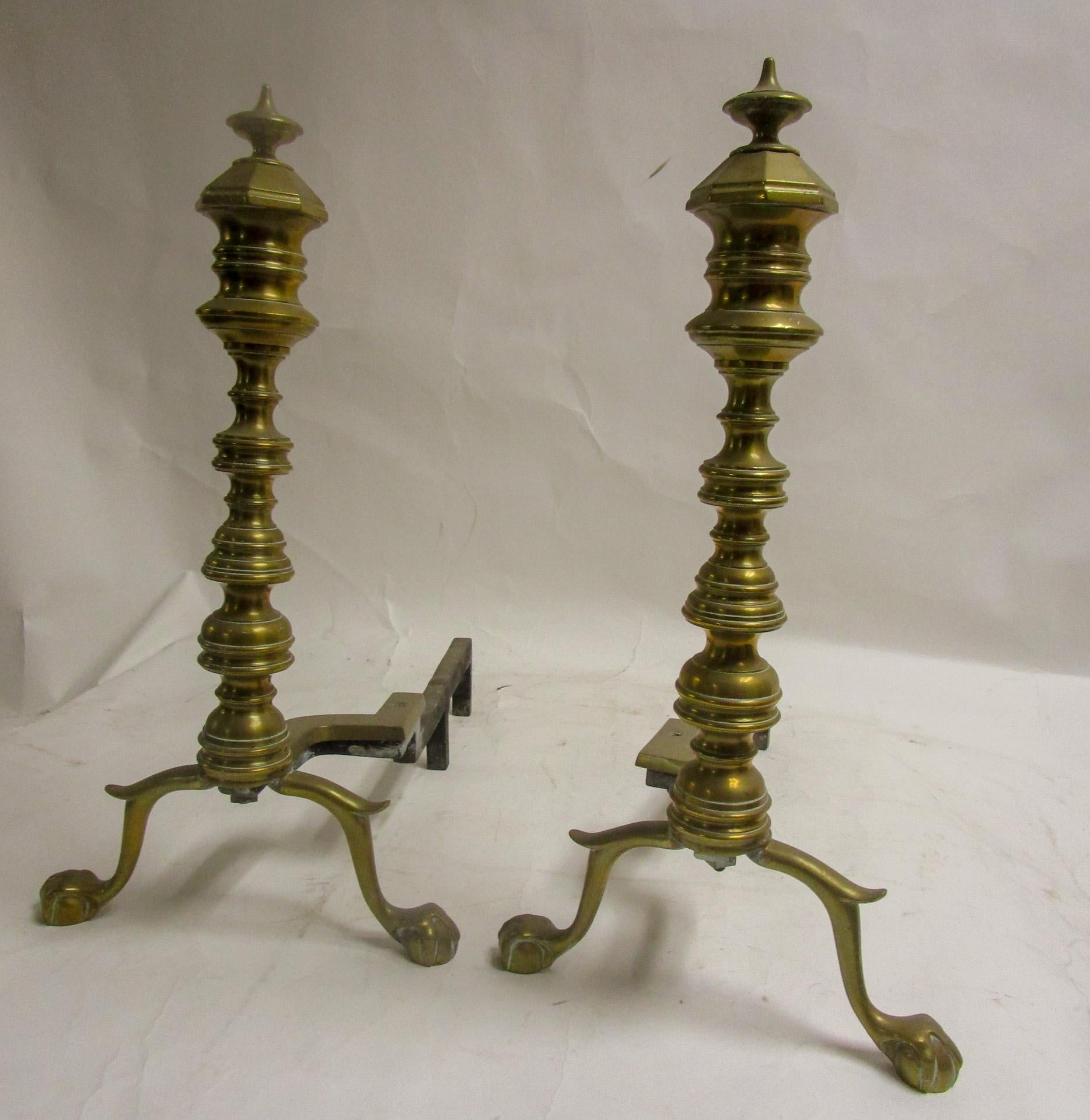This late 19th century Victorian English brass andiron firedog pair feature ball and claw feet and mutiple turnings topped off by ornate finials.