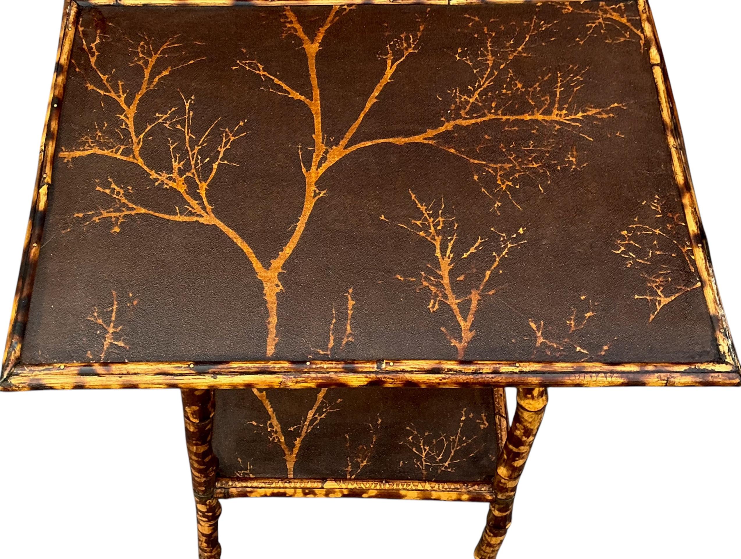 Il s'agit d'une table d'appoint en bambou brûlé de l'époque victorienne. Les deux étages ont été recouverts d'un papier peint à motif d'arbre, conforme à l'époque du Mouvement esthétique. Il est en très bon état d'ancienneté.