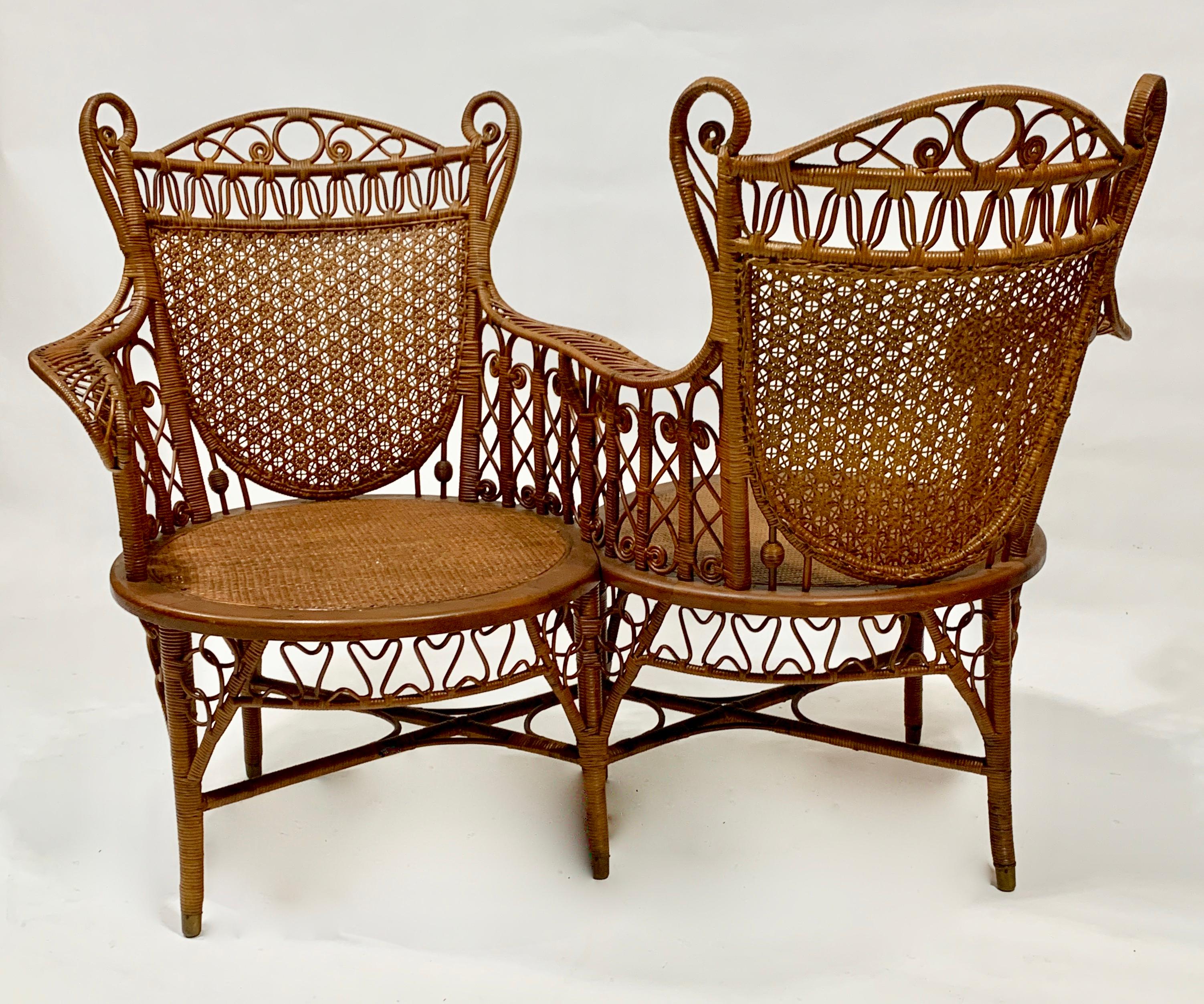 Cette chaise côte à côte est tressée dans un design très gracieux dans une finition naturelle avec des appuis-tête en forme d'aile de cue curly qui sont assis au-dessus de dossiers cannelés à la main. Les accoudoirs confortables et élégants sont