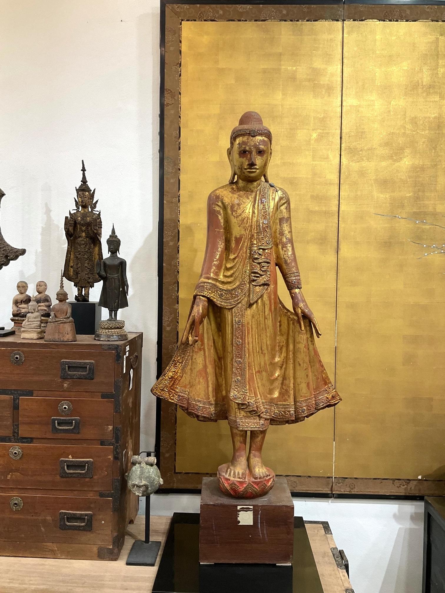 Bouddha debout - Période de Mandalay
Birmanie (Myanmar), 19e siècle
MATERIAL : Bois avec dorure d'origine et laque rouge
Dimensions : 106 × 55 cm

Ce Bouddha debout, imposant et élégamment détaillé, est un bel exemple de sculpture dévotionnelle de