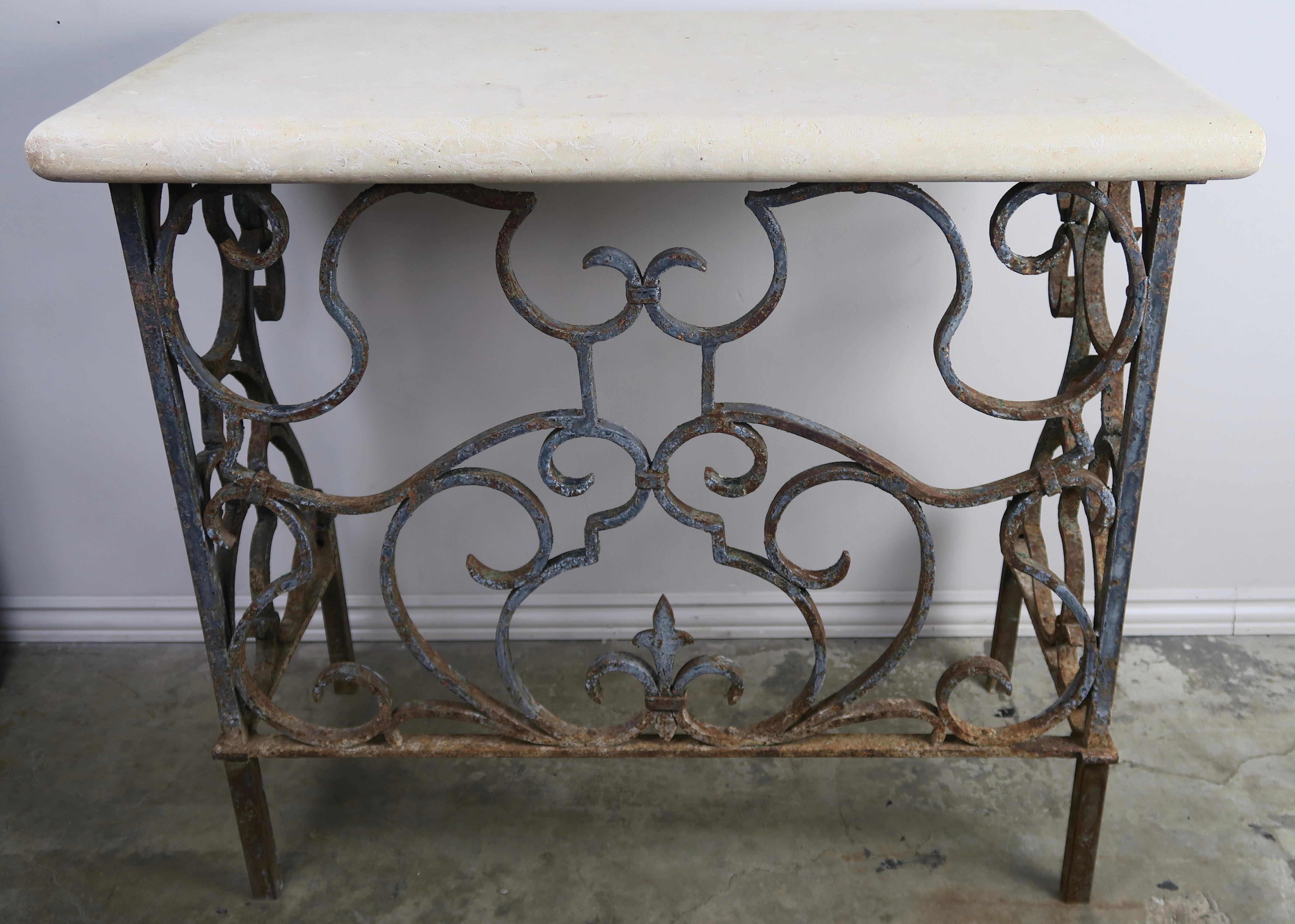19th century handwrought iron console base that supports a travertine top. Remnants of original paint can be seen throughout.