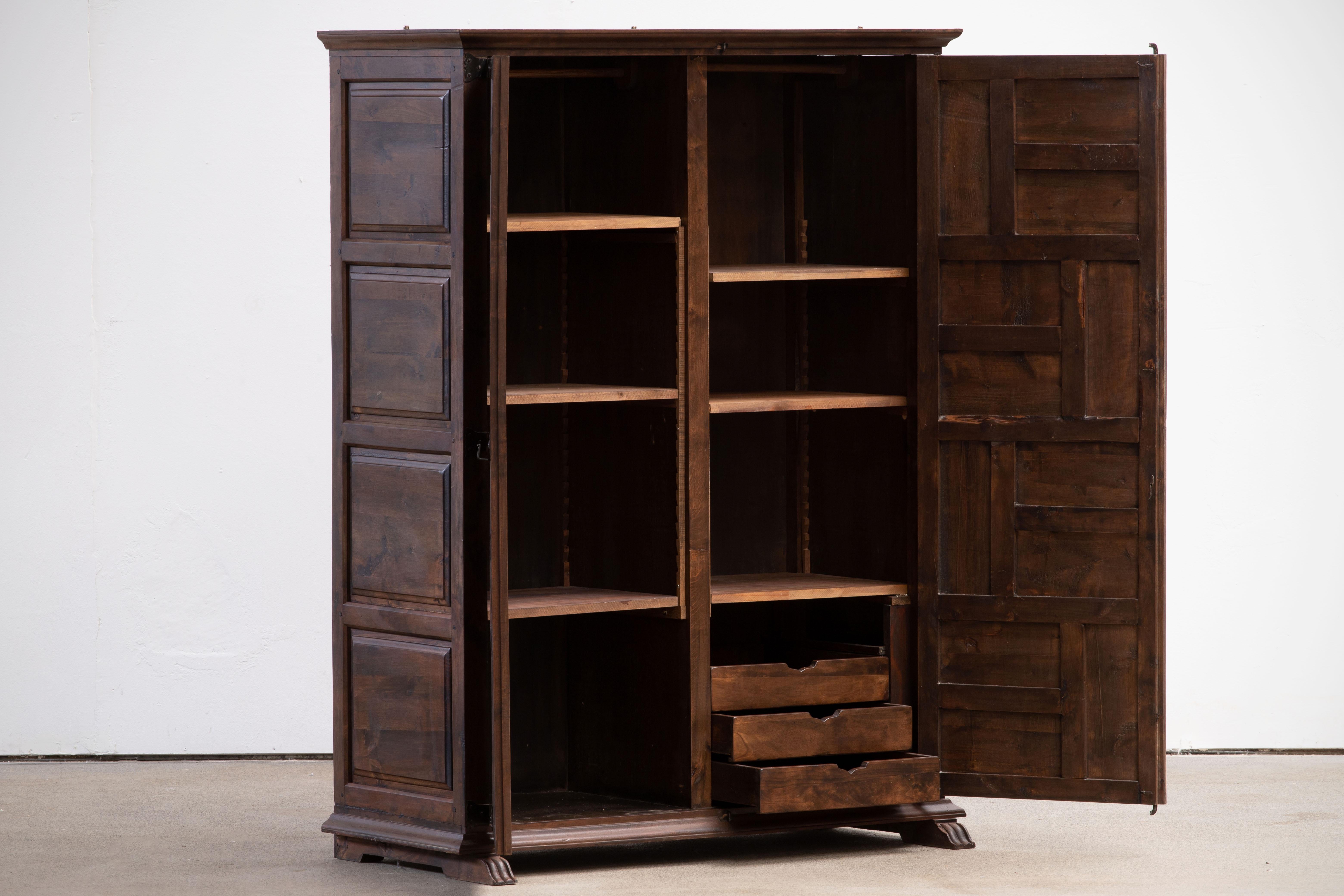 From Northern Spain, constructed of solid walnut, the rectangular top with molded edge a top a conforming case housing shelves and three drawers, the doors paneled with solid walnut, raised on a plinth base.
 
