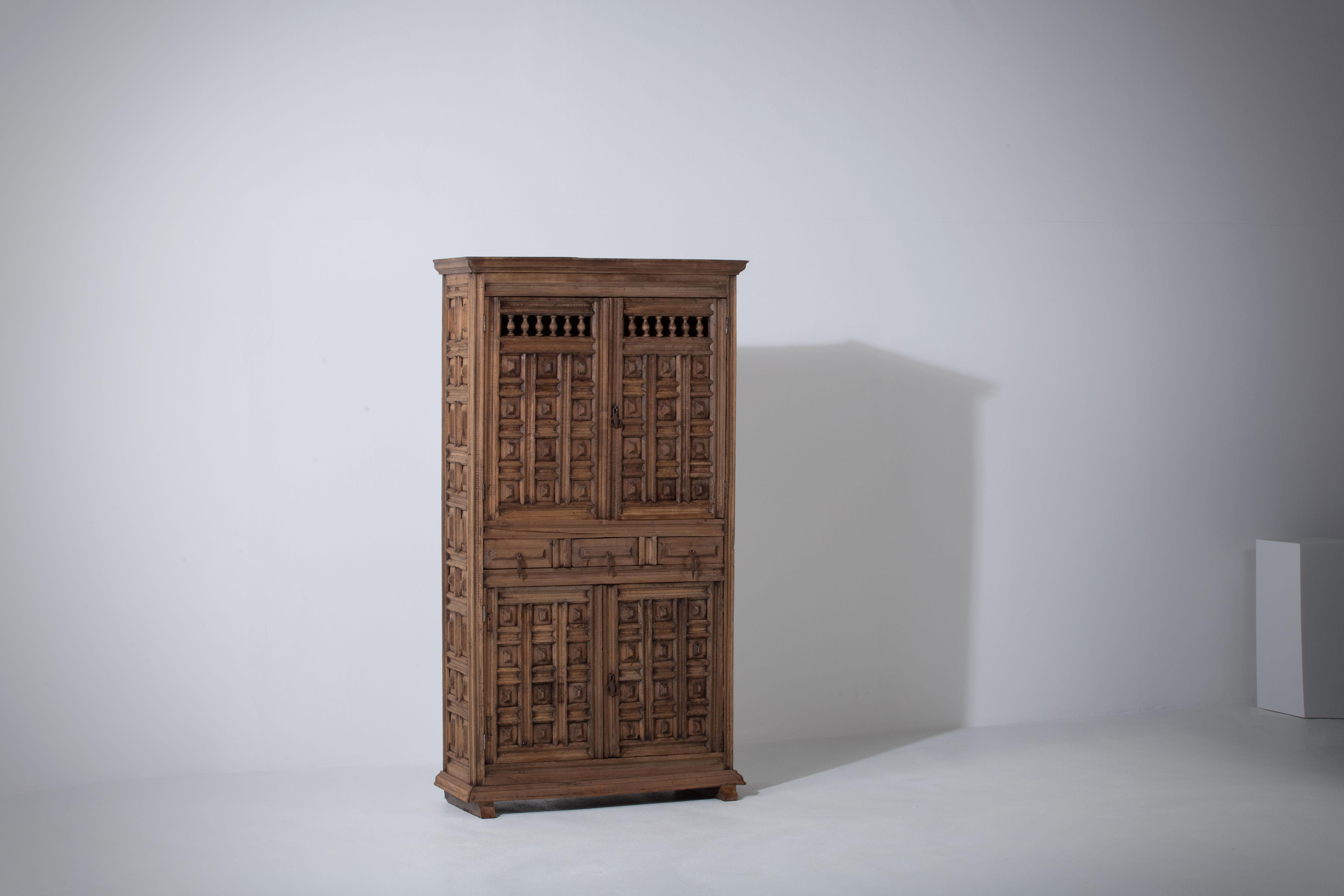 From Northern Spain, constructed of solid walnut, the rectangular top with molded edge a top a conforming case housing shelves and three drawers, the doors paneled with solid walnut, raised on a plinth base.
 