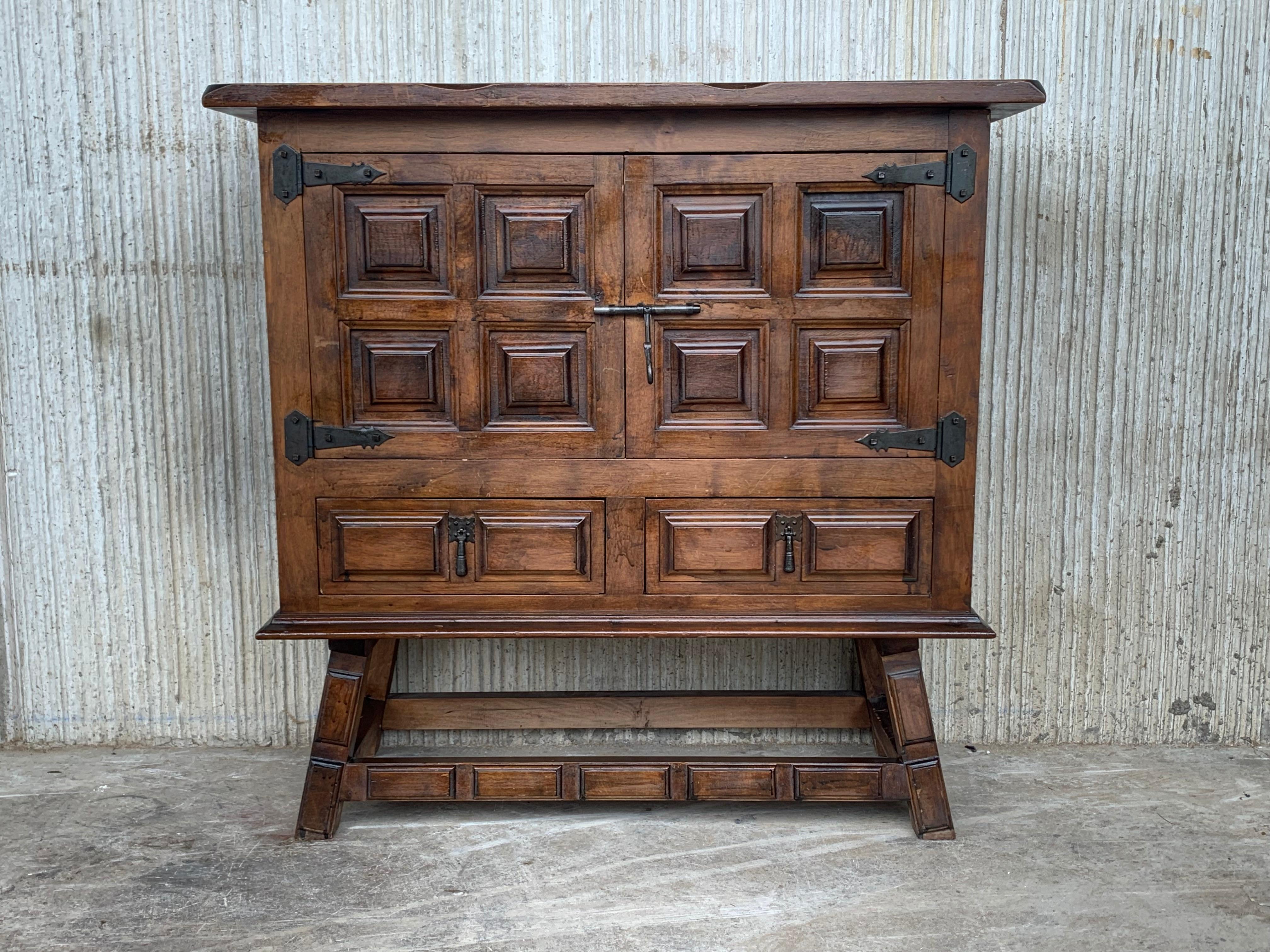 From Northern Spain, constructed of solid walnut, the rectangular top with molded edge atop a conforming case housing two doors paneled with solid walnut, two drawers on the low part and raised on four round legs.
Carved on the molding sides of the