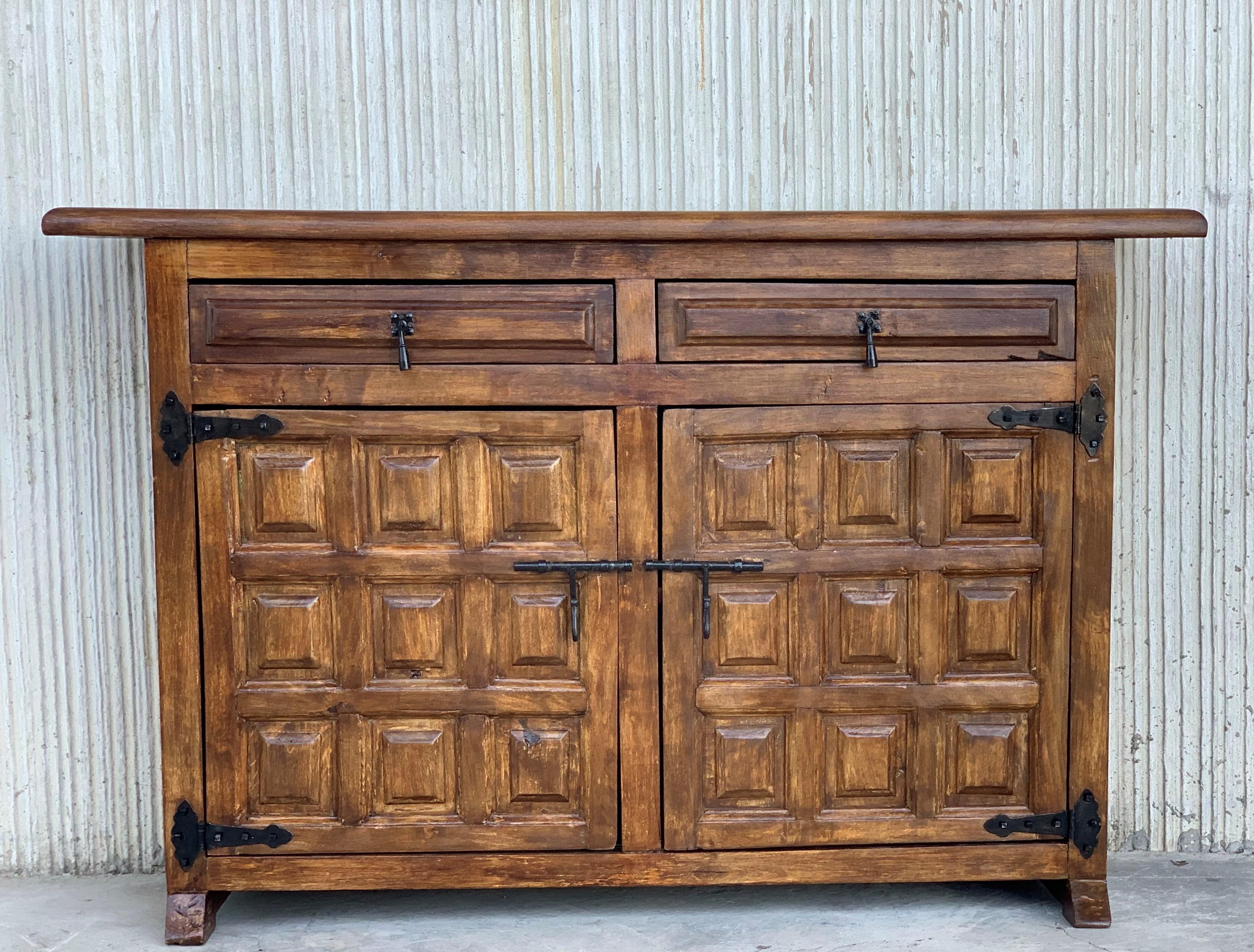 From Northern Spain, constructed of solid walnut, the rectangular top with molded edge atop a conforming case housing two drawers over two doors, the doors panelled with solid walnut, raised on a plinth base.
