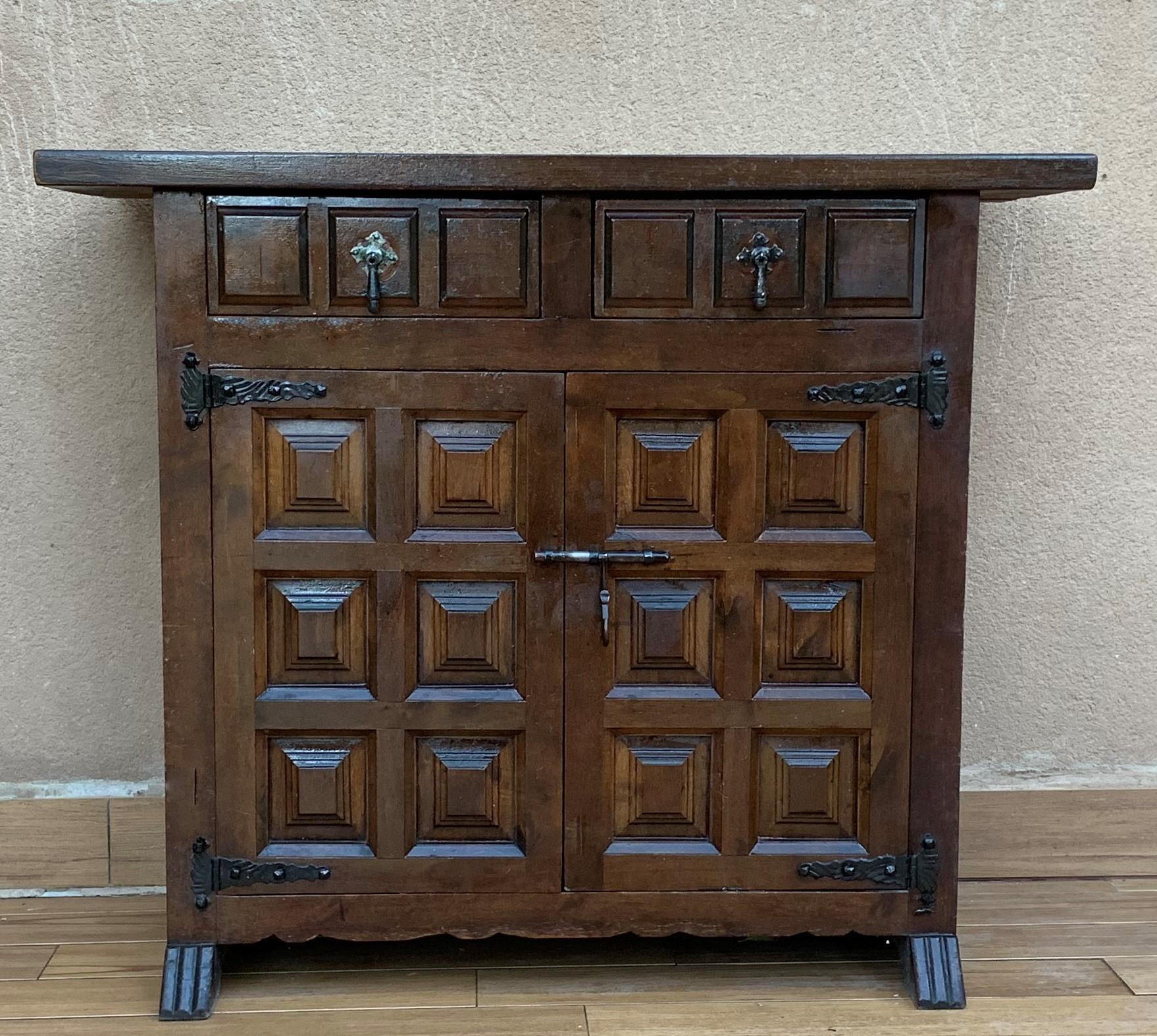 From Northern Spain, constructed of solid walnut, the rectangular top with molded edge atop a conforming case housing two drawers over two doors, the doors paneled with solid walnut, raised on a plinth base.

   